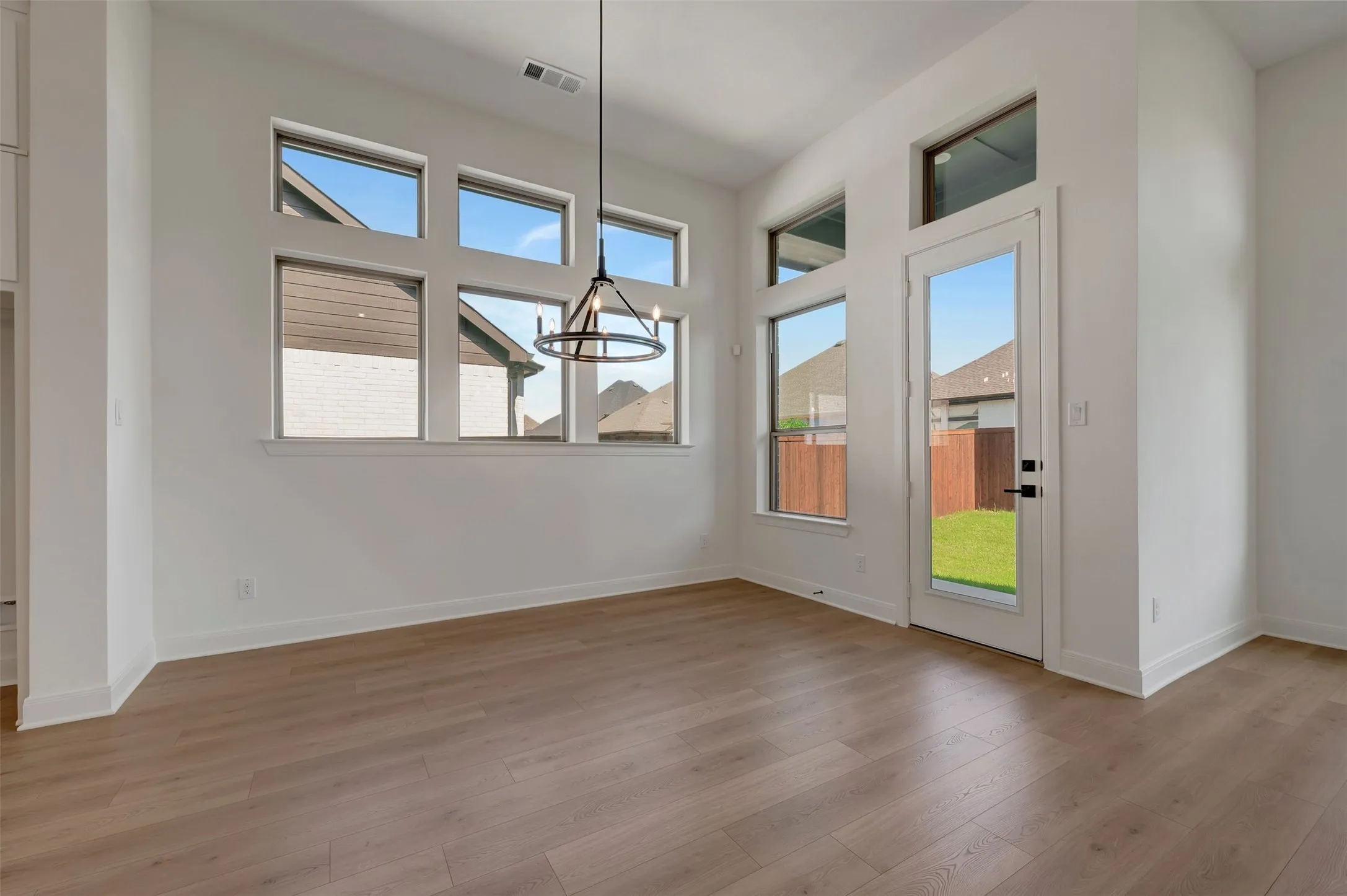 Wood-finish flooring, multiple transom windows, and a modern chandelier