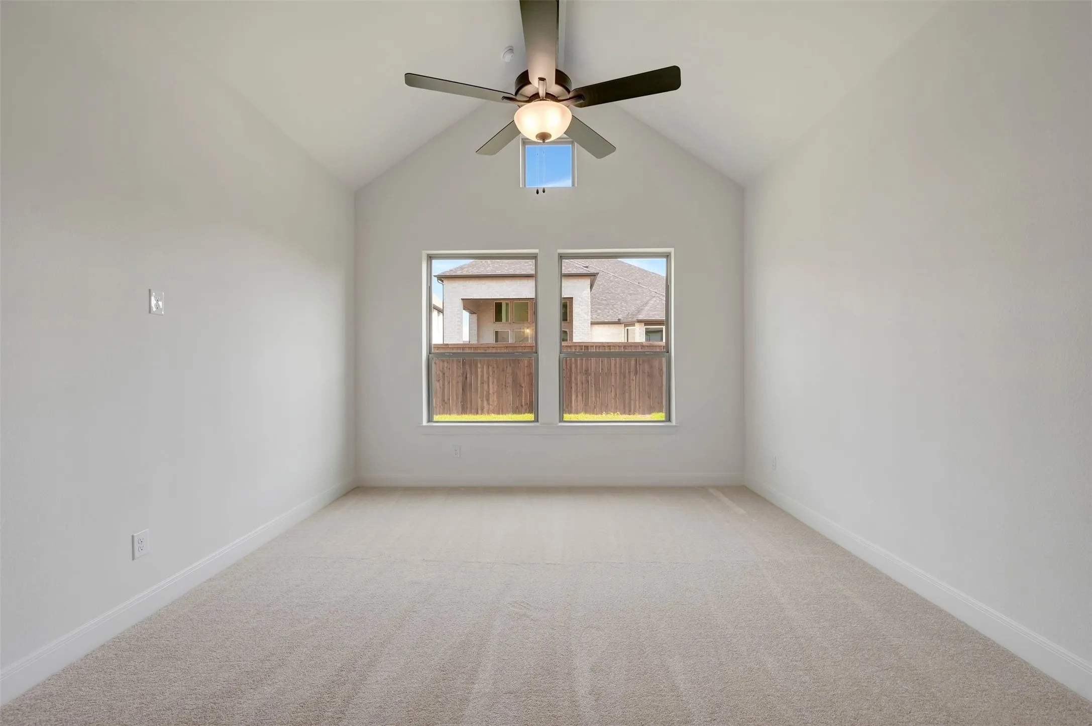 Vaulted ceiling with an attached ceiling fan, dual windows, and light-toned carpeting
