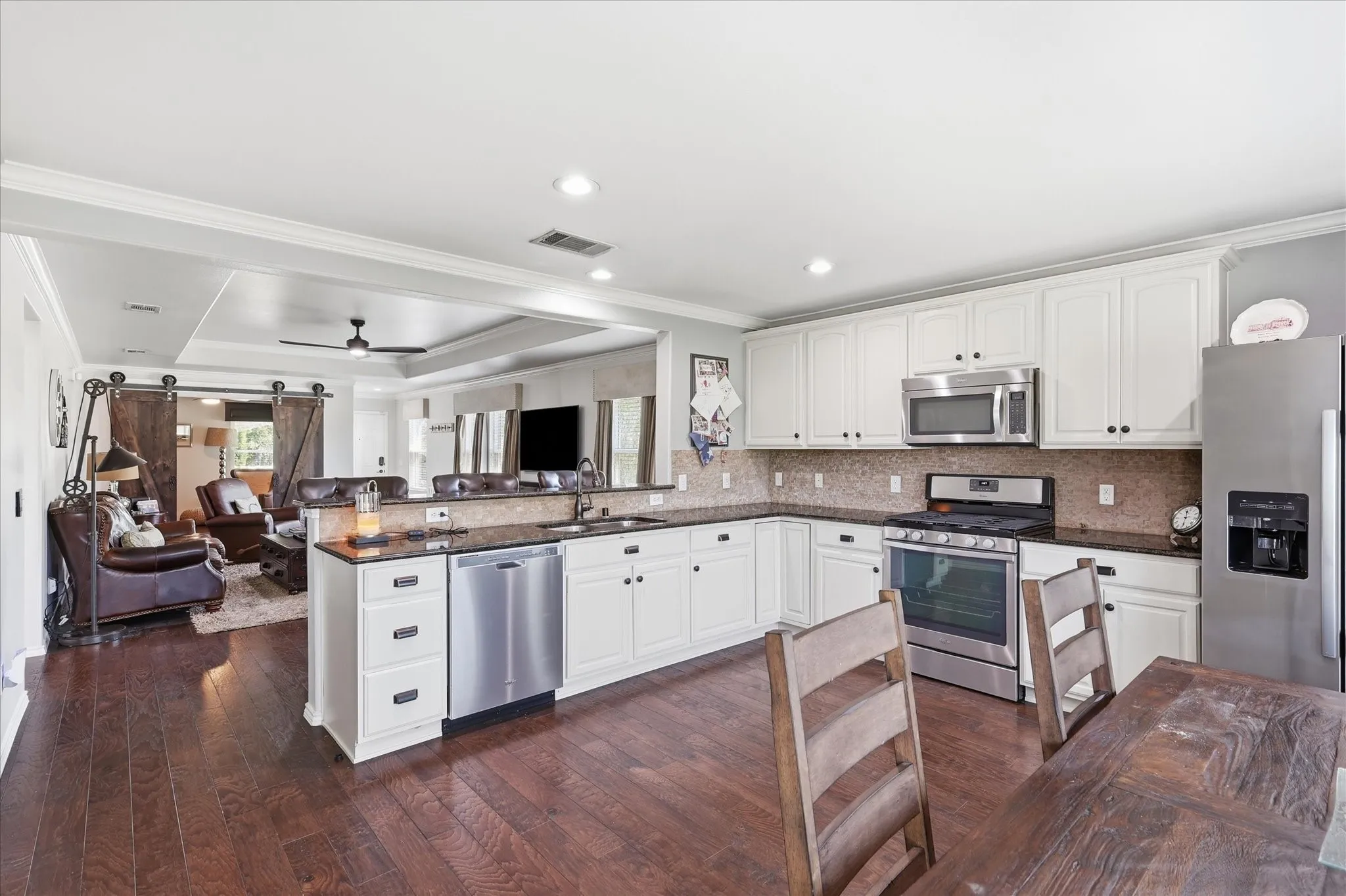 Kitchen featuring rich wood-finish flooring, white cabinetry, dark countertops, and stainless steel appliances