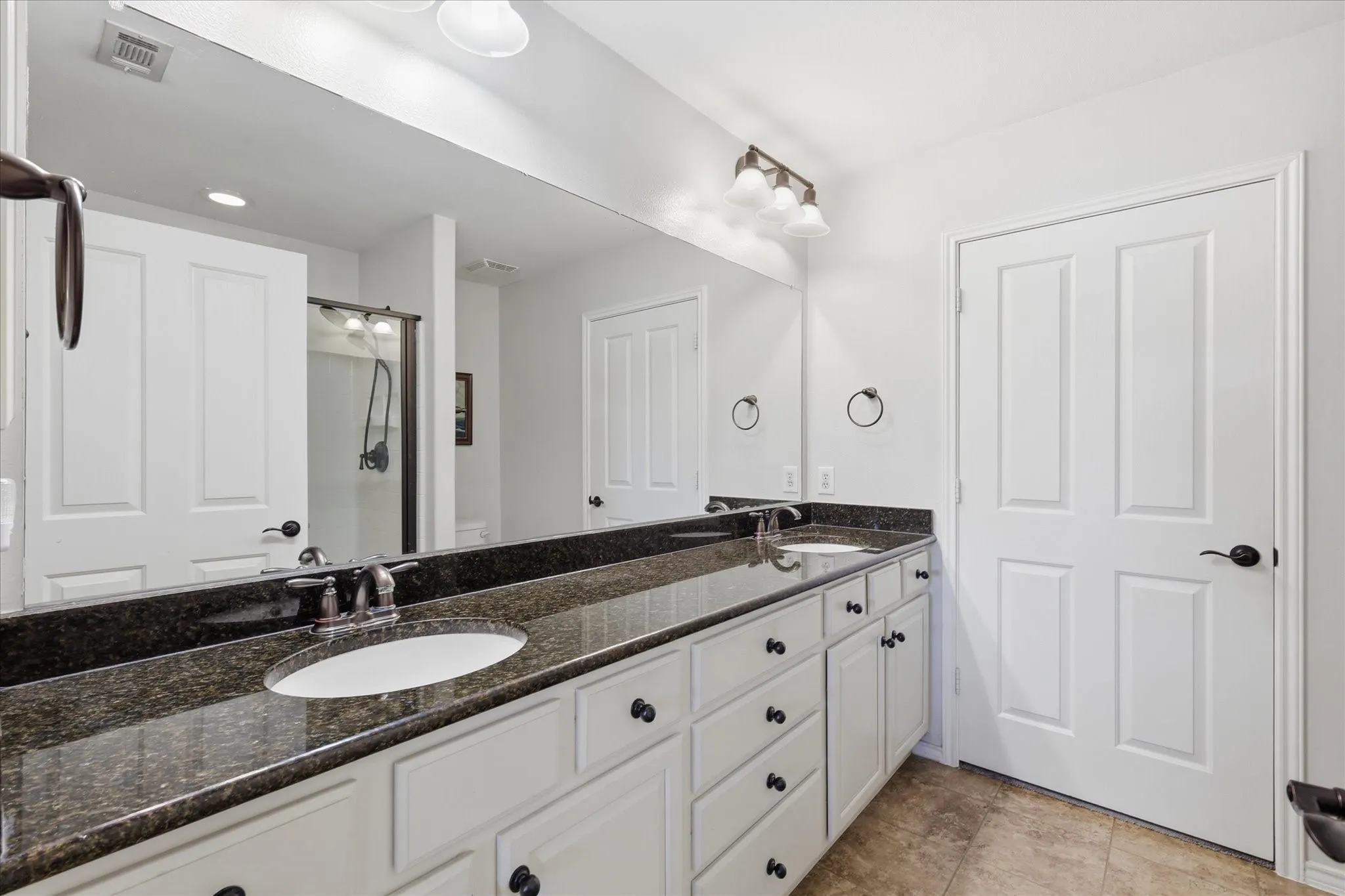 Dual oval undermount sinks set within a speckled dark countertop