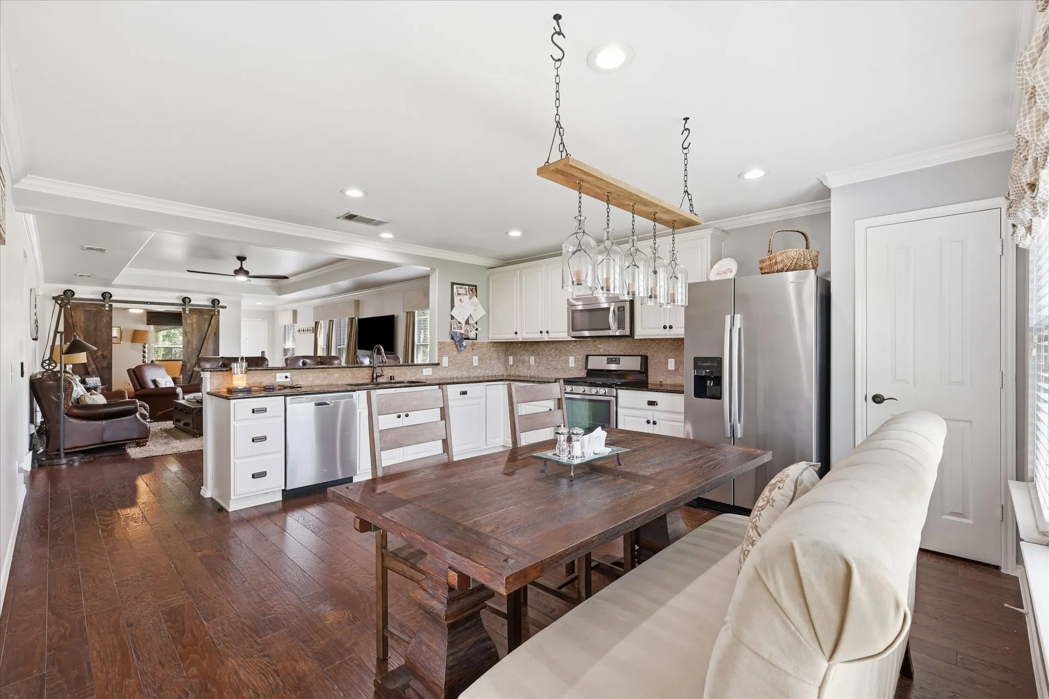Kitchen featuring wood-finish flooring, white cabinetry, stainless steel appliances, and a tile backsplash