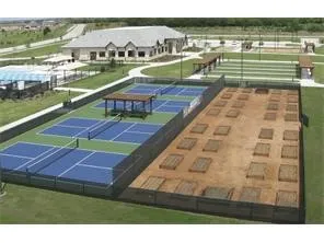 Community recreation area featuring multiple courts, a large building, and a garden plot area