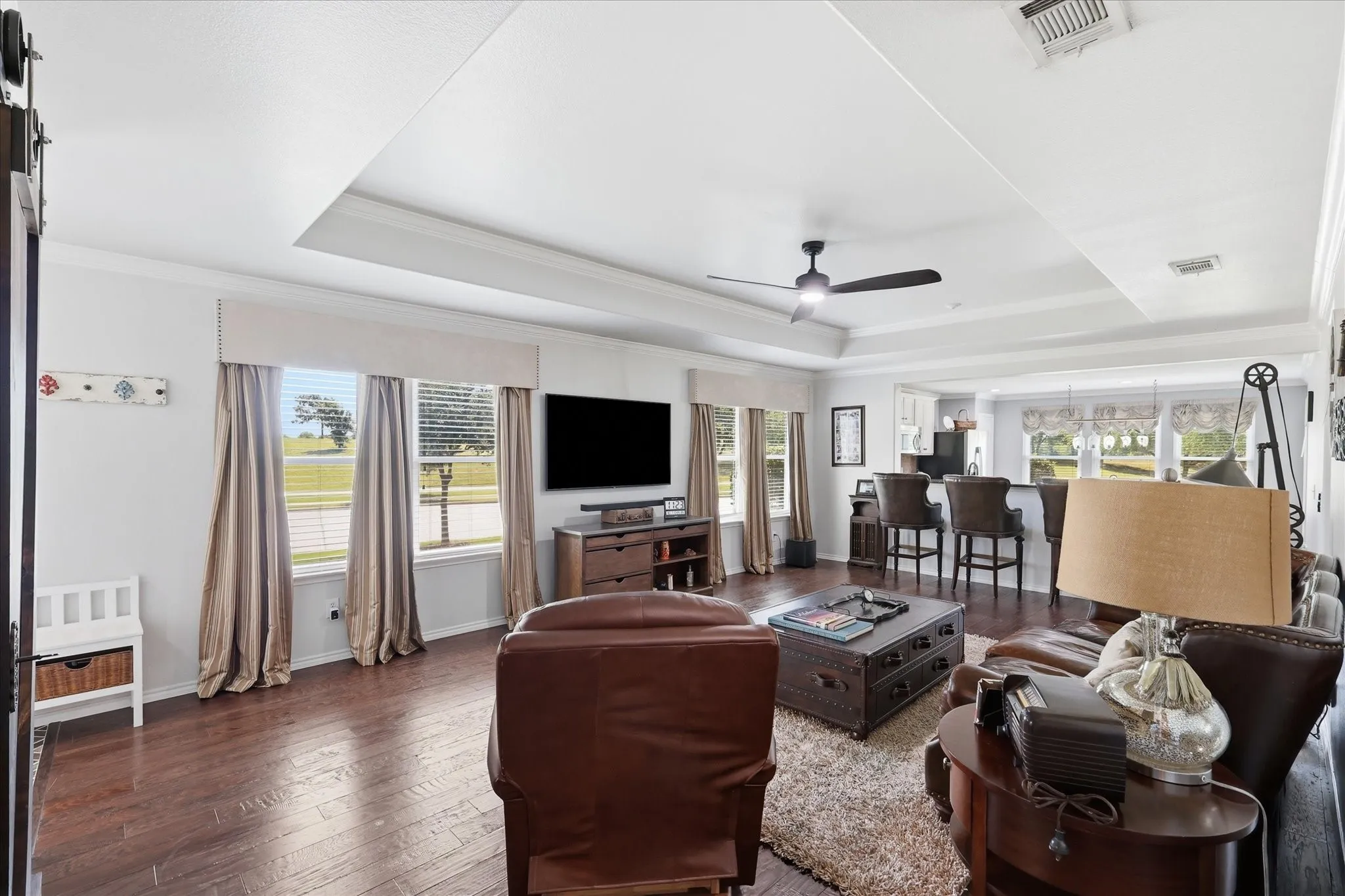Spacious living area featuring wood-finish flooring, a tray ceiling, and crown molding
