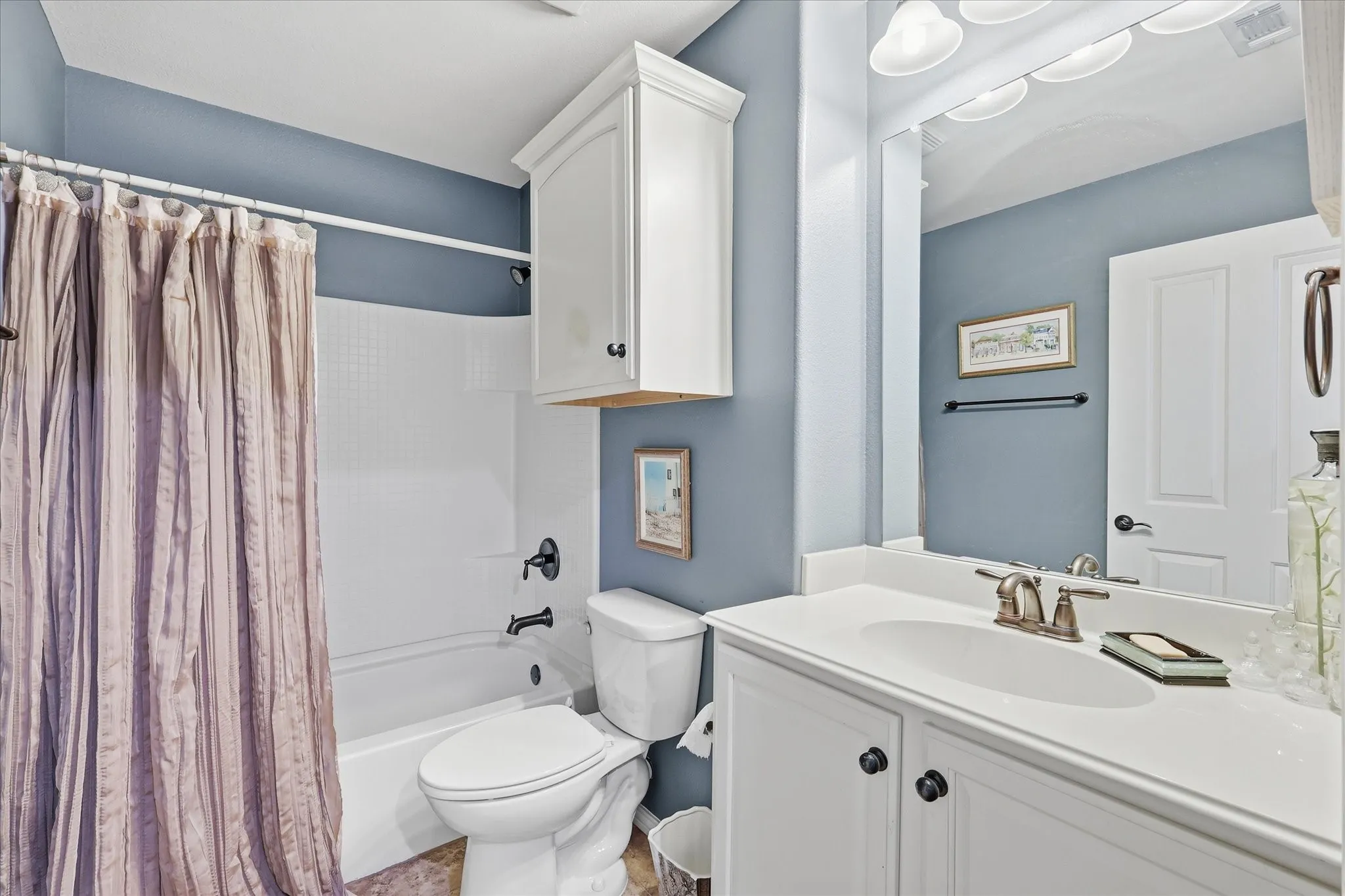Bathroom featuring a white vanity with integrated sink, brushed nickel faucet, large wall mirror, and white cabinetry