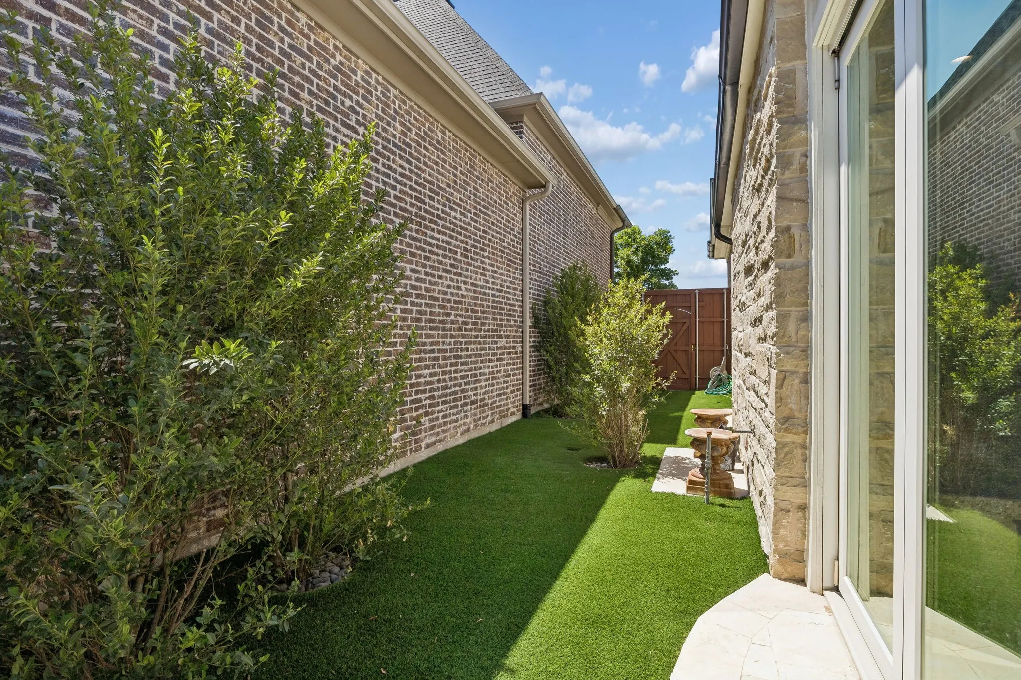 Long shot of the artificial turf side yard and trees.