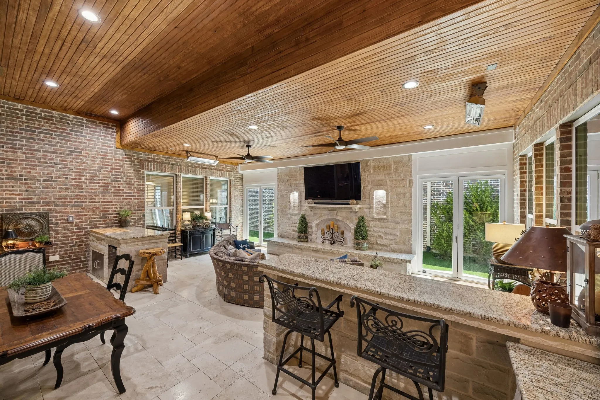 And WOW... the crown jewel of this incredible home.. This additional 620 square foot living space was created with high-end upgrades. The ceiling is one-of-a-kind with tiered tongue in groove detail. Stone wall detail with mantle and hearth to add candles for a warmth atmosphere, an additional dining area, travertine stone flooring, Marvin folding doors.