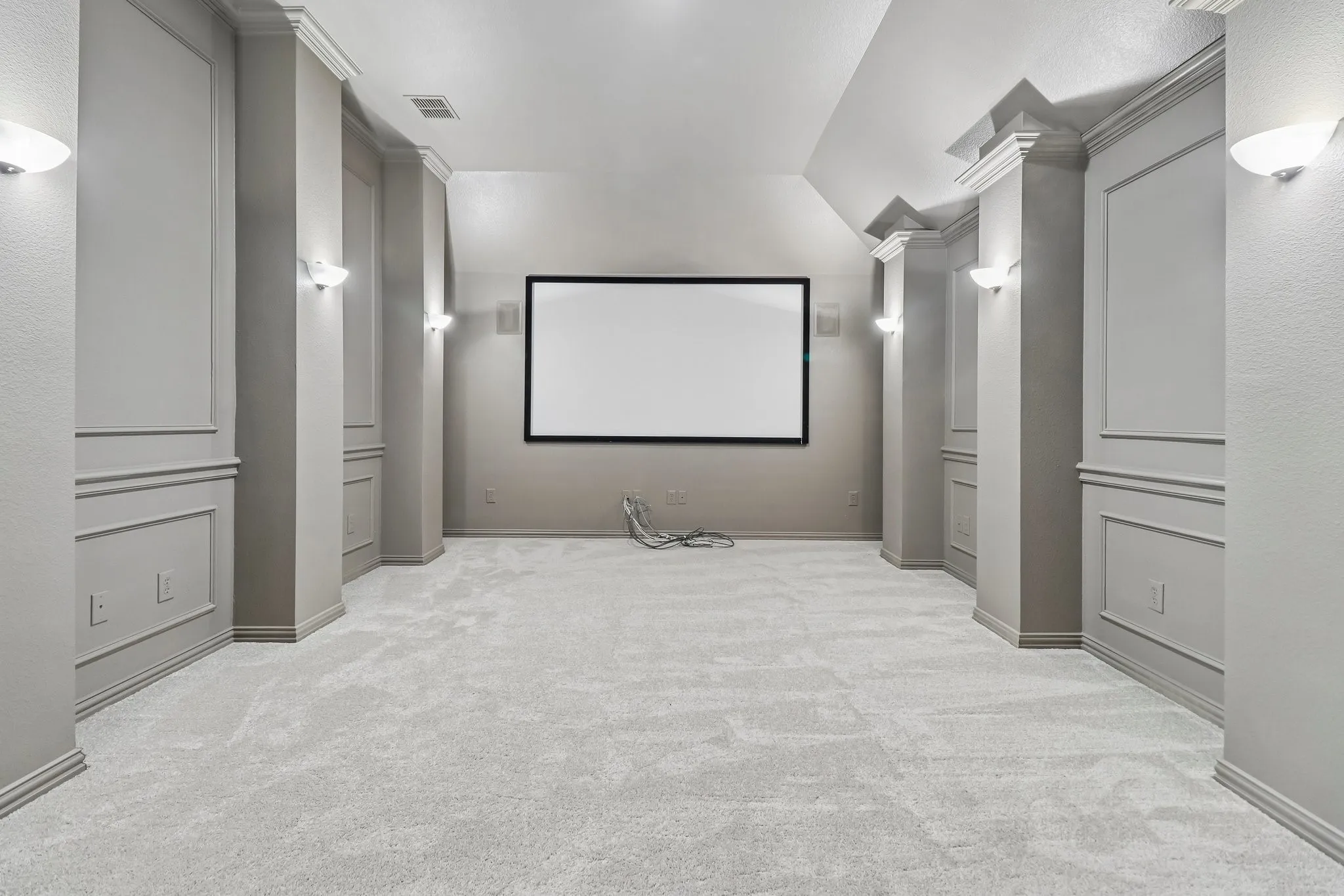 Dedicated media room featuring a large projection screen, in wall front speakers, dimmable sconce lighting and media projector.