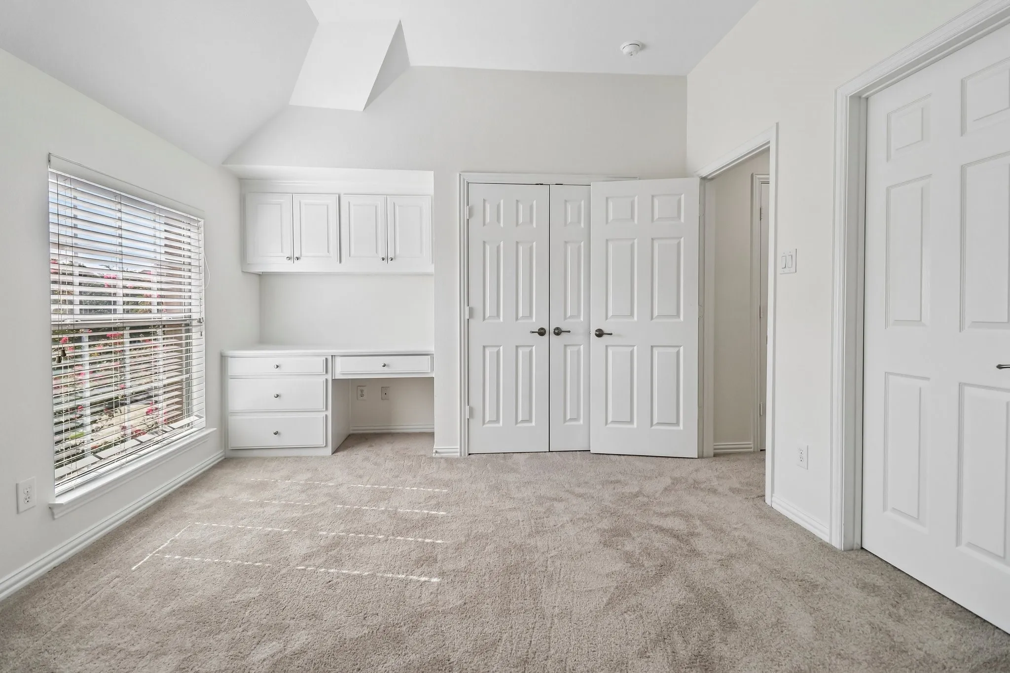 Large bedroom with vaulted ceilings, double closet and built in desk.