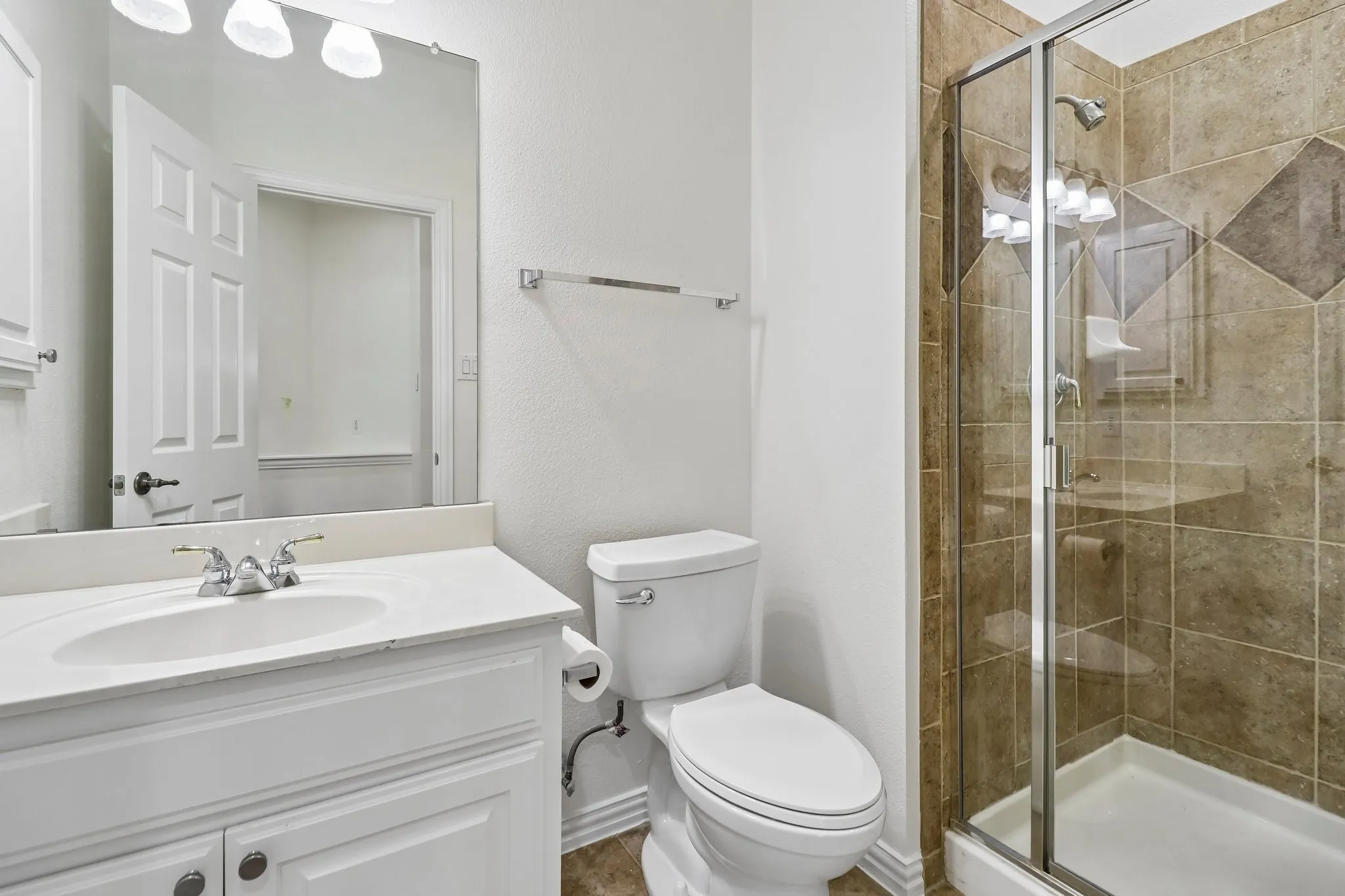 Downstairs guest bathroom featuring a glass-enclosed shower with tile surround, a single vanity with an integrated sink, and new elongated toilet.