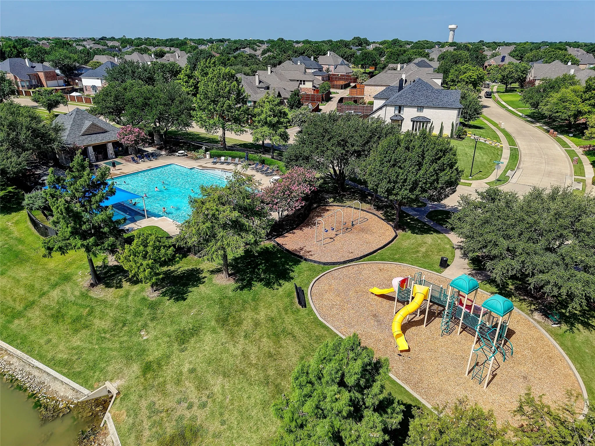 Community amenity area featuring a large swimming pool, covered outdoor seating, and a playground