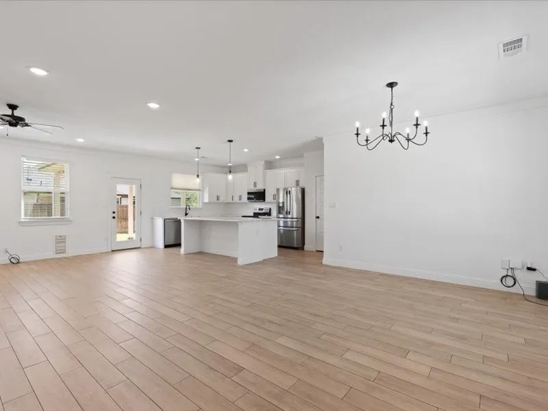 Open-concept living space featuring wood-look tile flooring and white walls