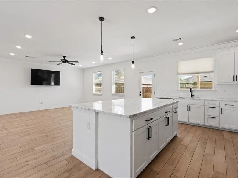 Modern kitchen island featuring a white countertop, two pendant lights, and ample storage cabinetry