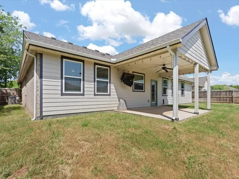 Rear exterior with covered patio featuring a ceiling fan and string lighting
