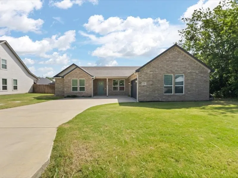 Brick veneer exterior with a contrasting teal entry door, a multi-car concrete driveway, a gabled roofline, and an integrated garage