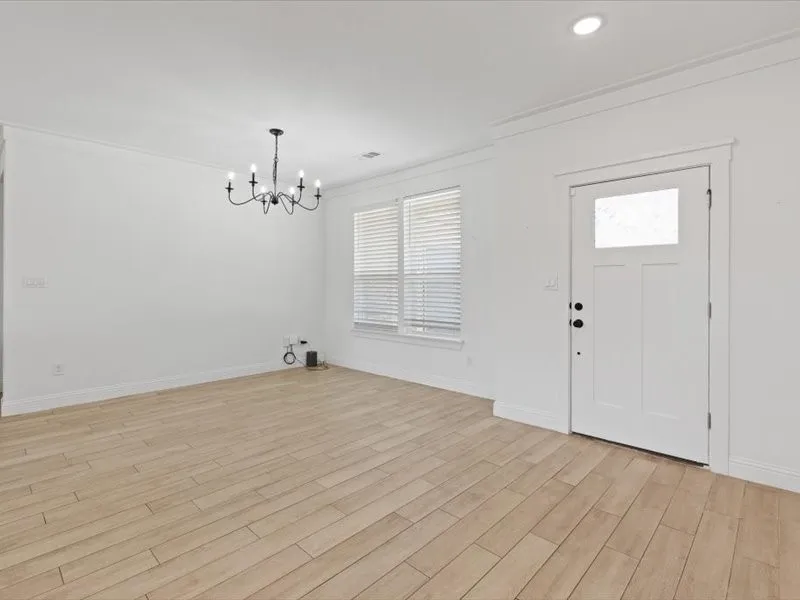Bright living area featuring wood-finish flooring, white walls, and crown molding