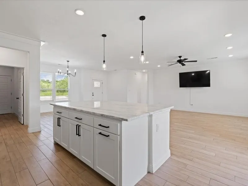 Kitchen island featuring white cabinetry, dark hardware, and a light-toned stone countertop
