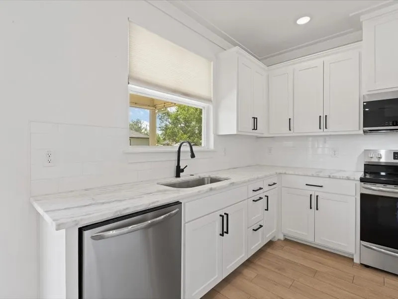 Kitchen featuring white shaker cabinetry, stainless steel appliances, a subway tile backsplash, and wood-finish flooring