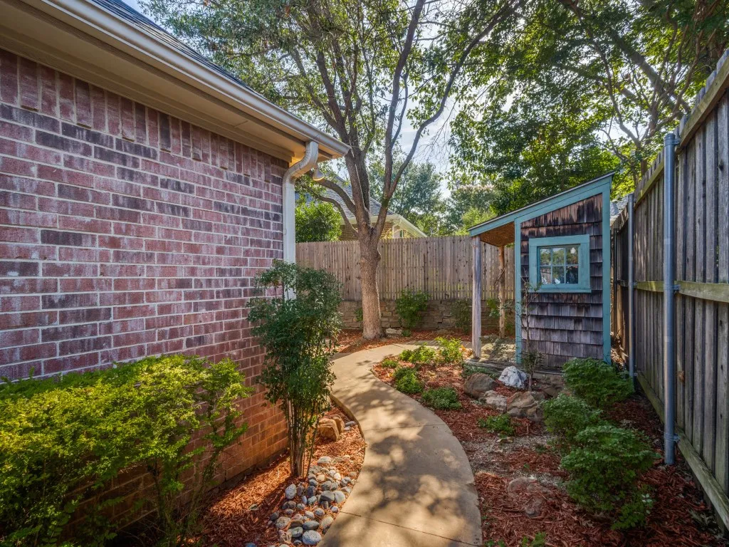 Follow the sidewalk from the front gate through the beautifully landscaped side yard. Charming storage shed has windows and a small covered porch. Wood privacy fence give you a private backyard.