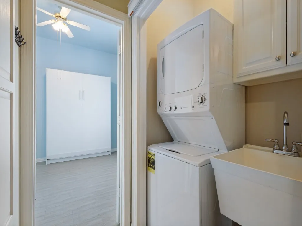 In this photo, you are standing in the hallway with the laundry closet on your right, a built-in ironing board on your left, and the 3rd guest bedroom is straight ahead. The laundry closet has a stackable washer and dryer, laundry sink and storage cabinet; everything you need in one convenient location.