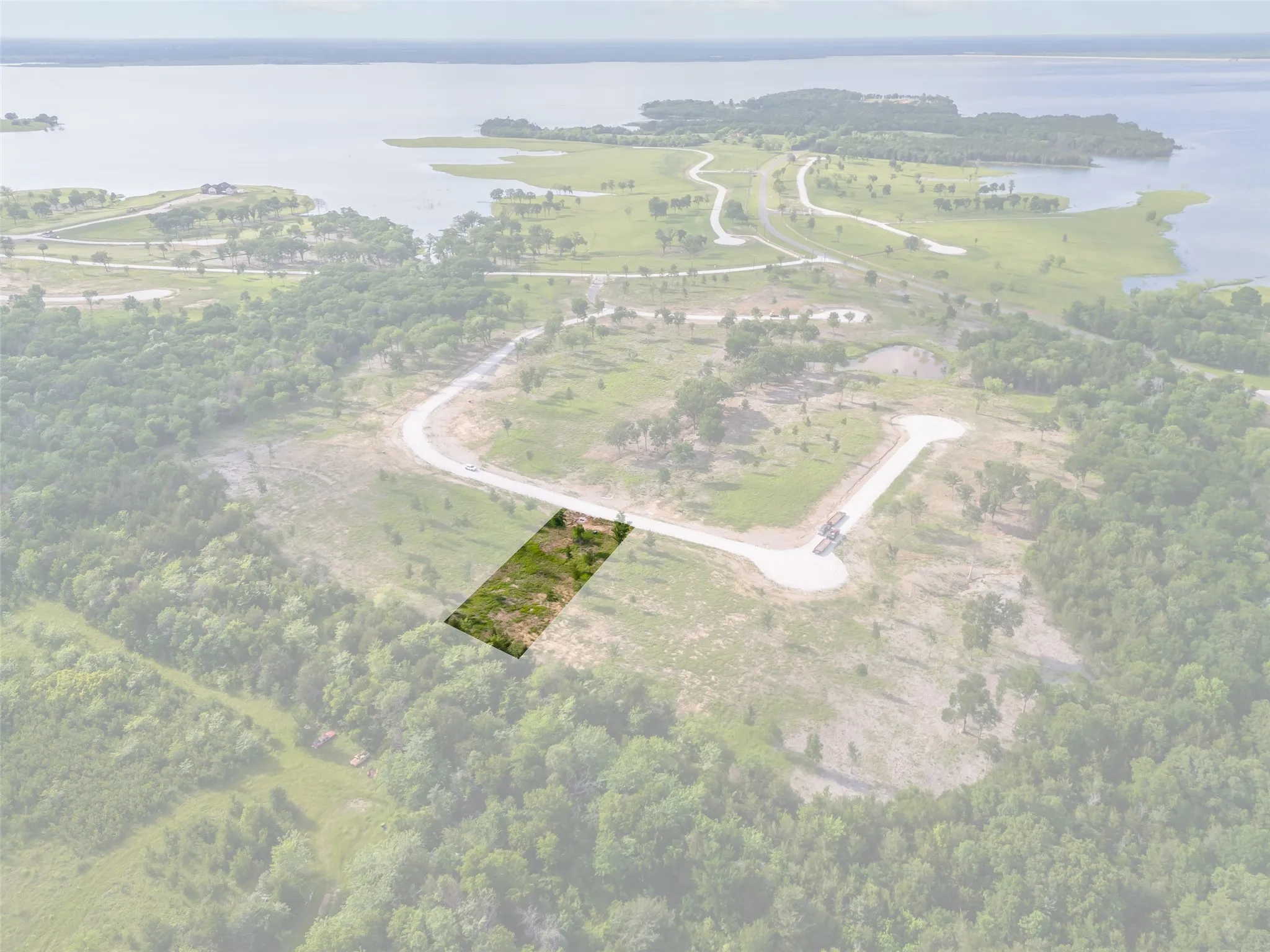 Drone view of the cul-de-sac street with Lot 144 outlined, showing a partially wooded, cleared building pad area at the end of a paved street, surrounded by mature trees with neighboring lots