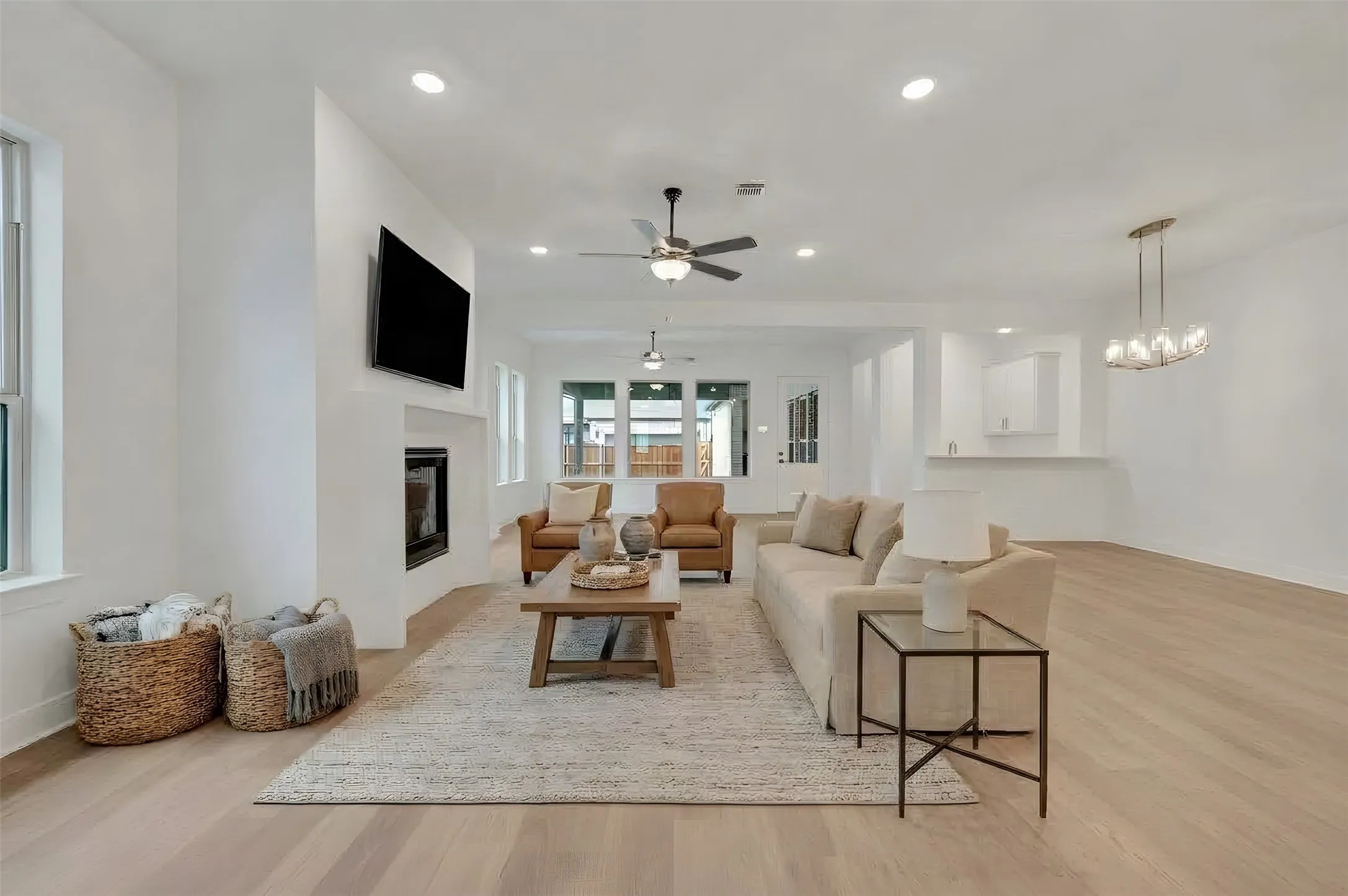 Open-concept living area featuring light wood-finish flooring, recessed lighting, and a contemporary fireplace