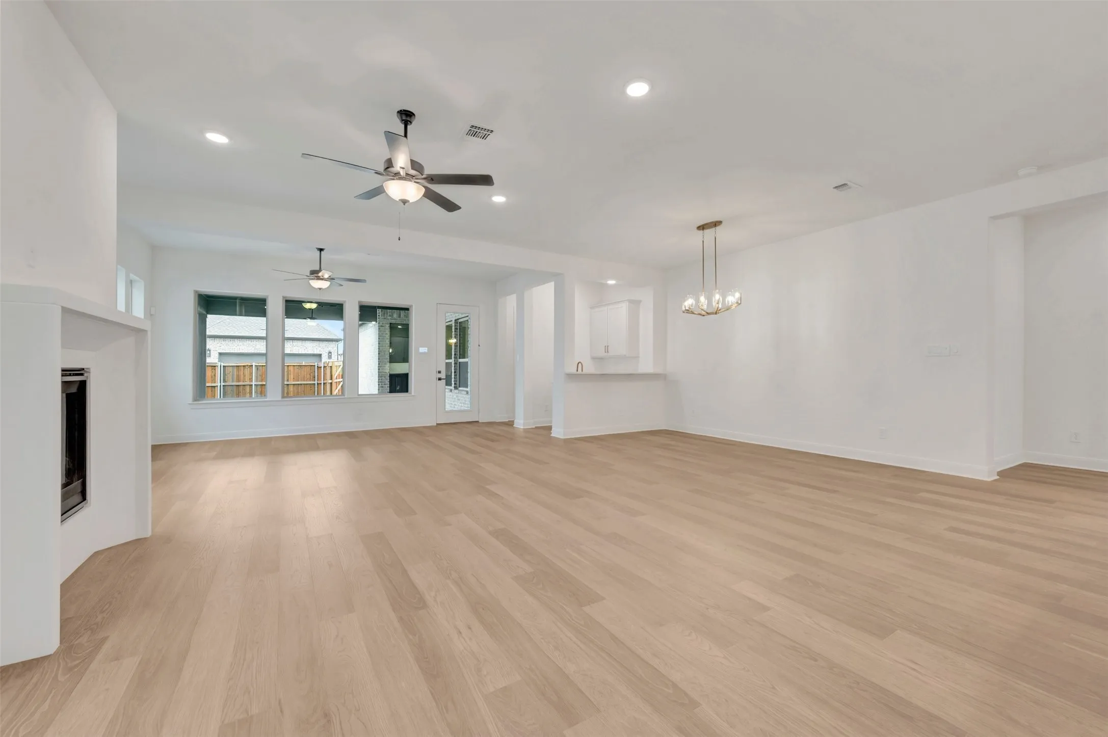 Expansive living area featuring wood-finish flooring, a built-in fireplace, multiple windows, and recessed lighting