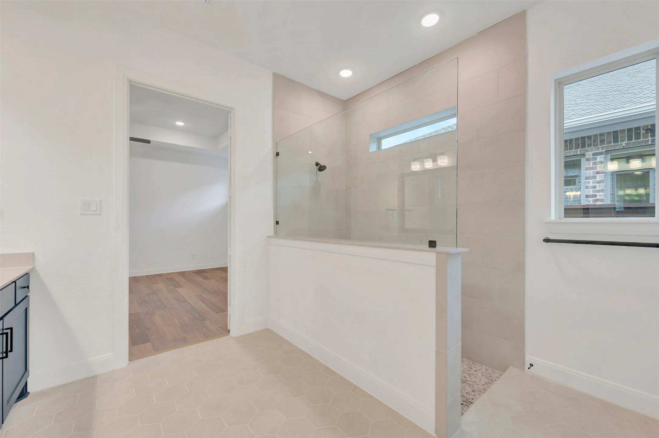 Walk-in shower with clear glass enclosure, tiled walls, and pebble-finish floor