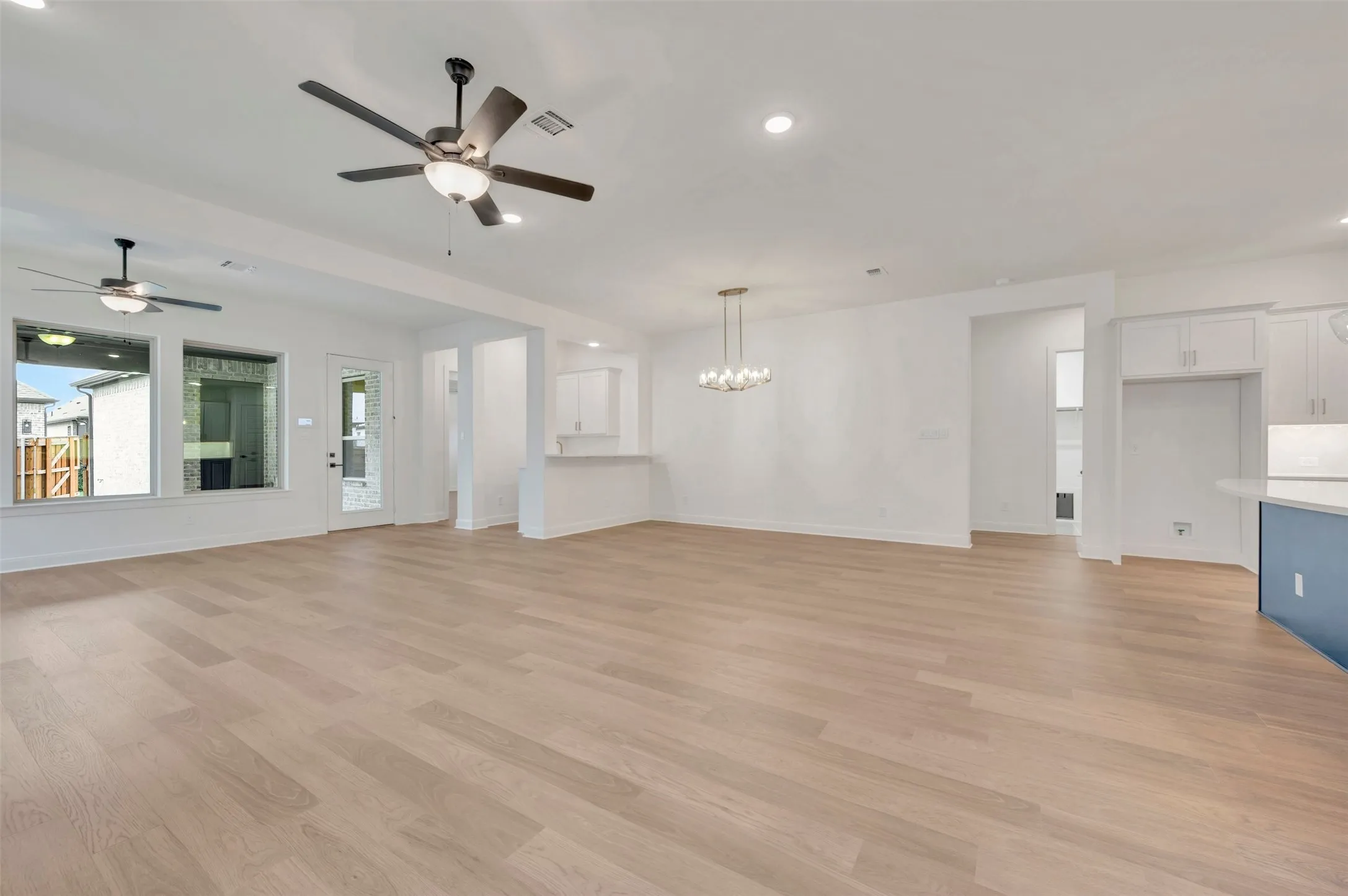 Expansive open-concept room with light wood-finish flooring, recessed lighting, and ceiling fans