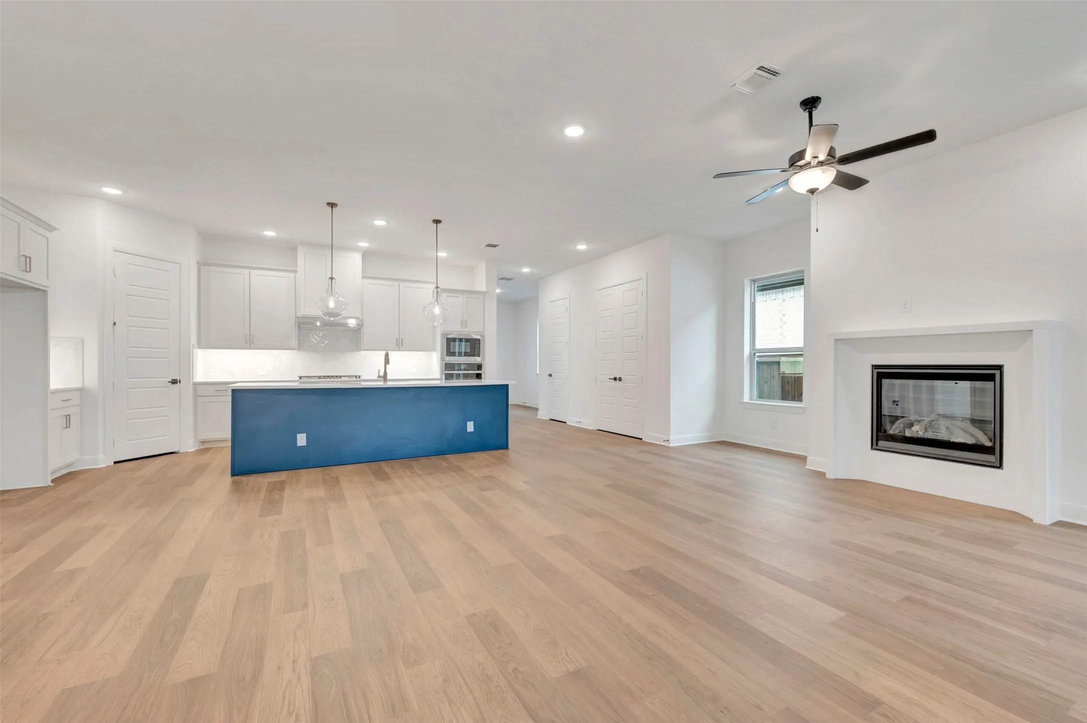Light wood-finish flooring with a white fireplace and black firebox