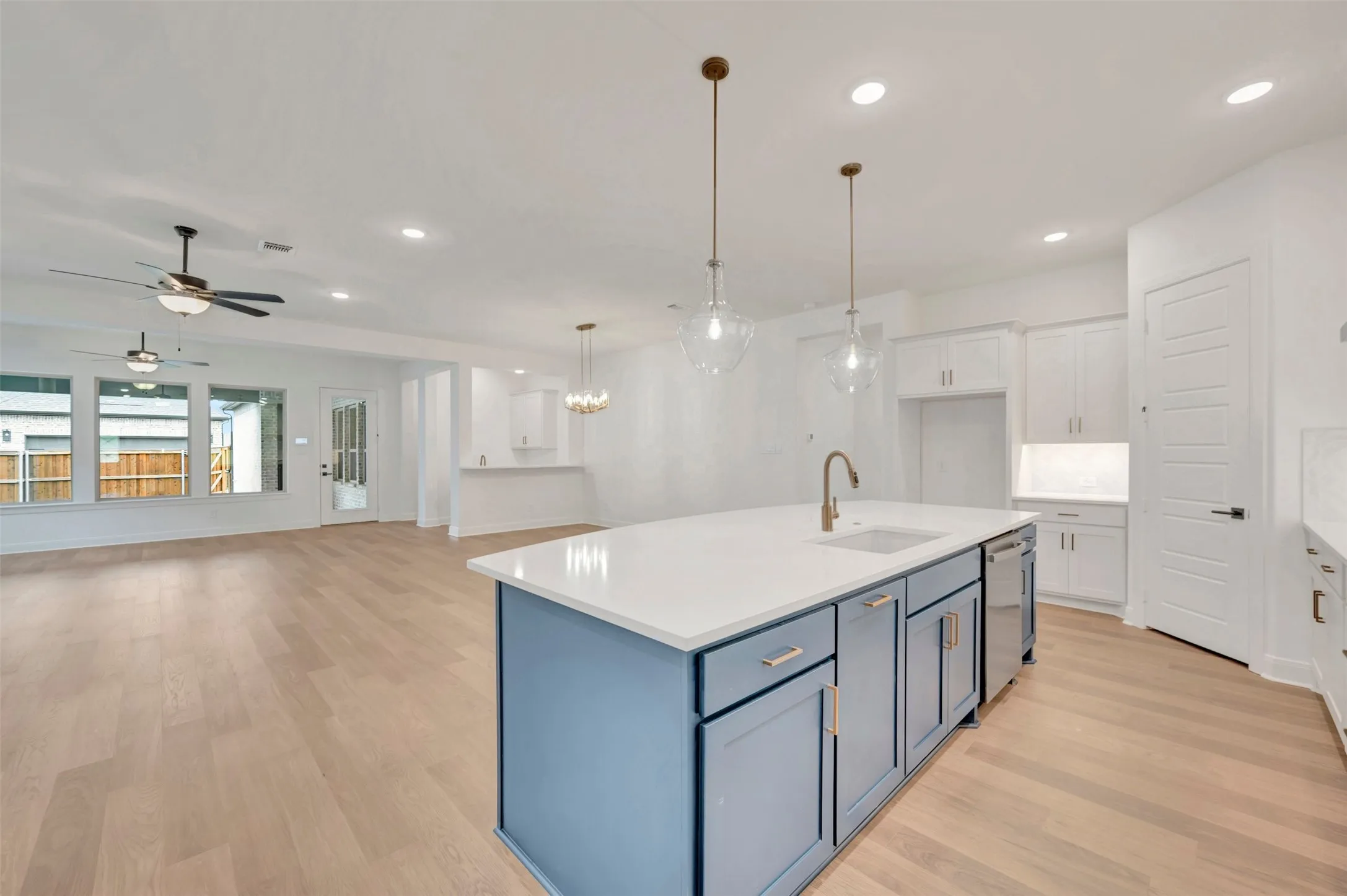 Open-concept kitchen and living area featuring wood-finish flooring, recessed lighting, and a kitchen island with a built-in sink