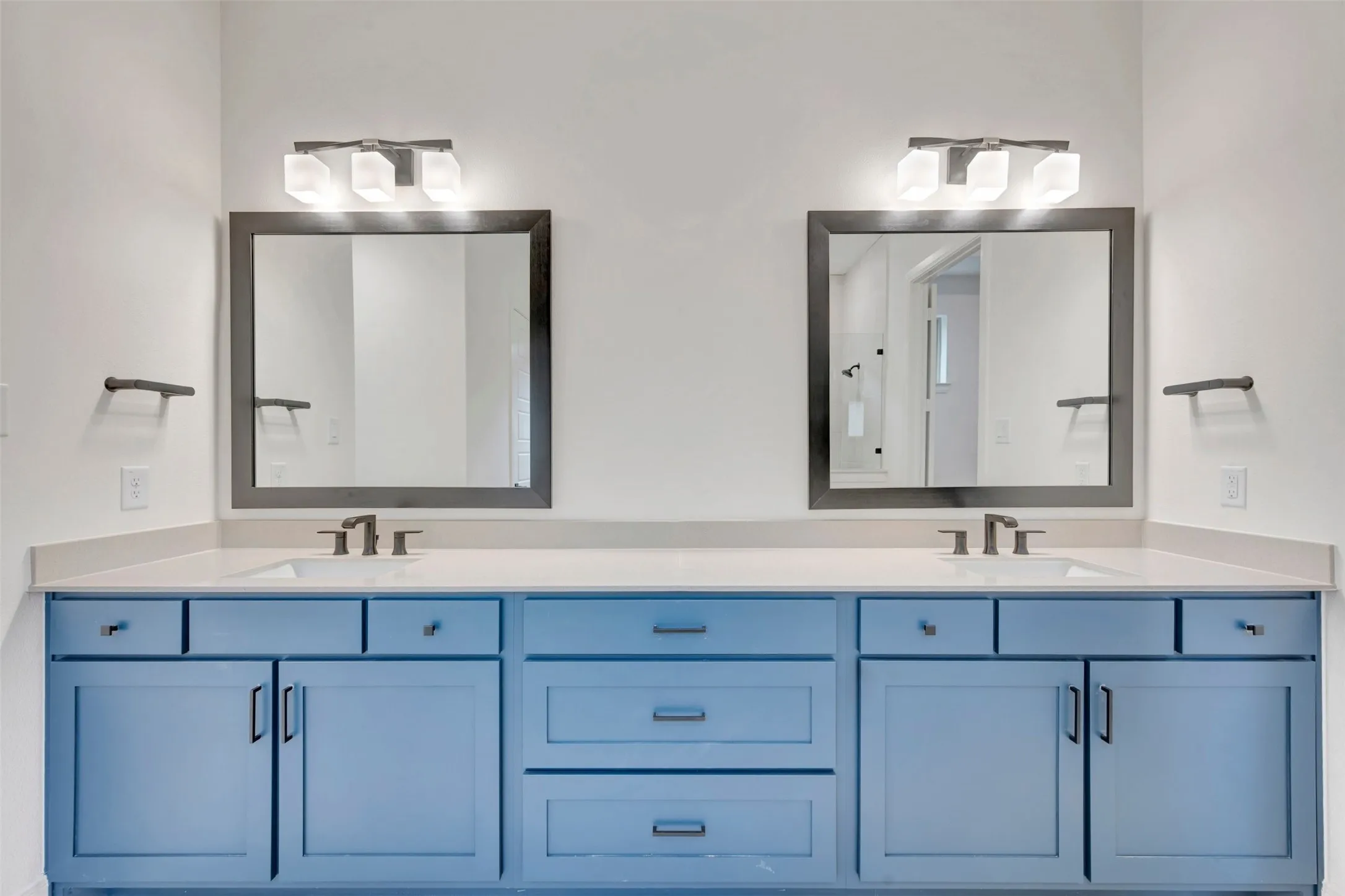 Dual vanity with light blue cabinetry, integrated sinks, and polished chrome fixtures