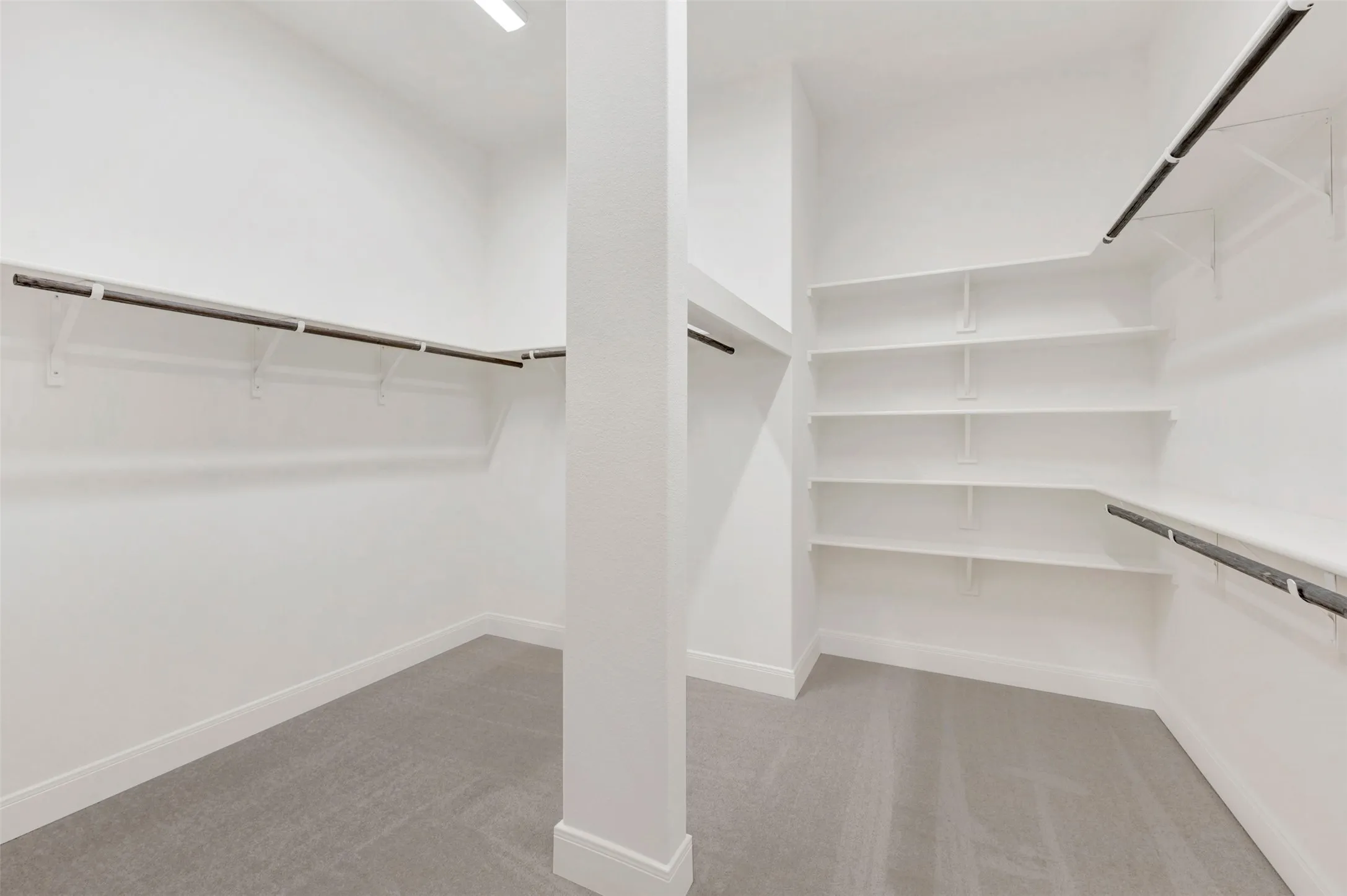 Walk-in closet with integrated shelving, multiple hanging rods, and light gray carpeting