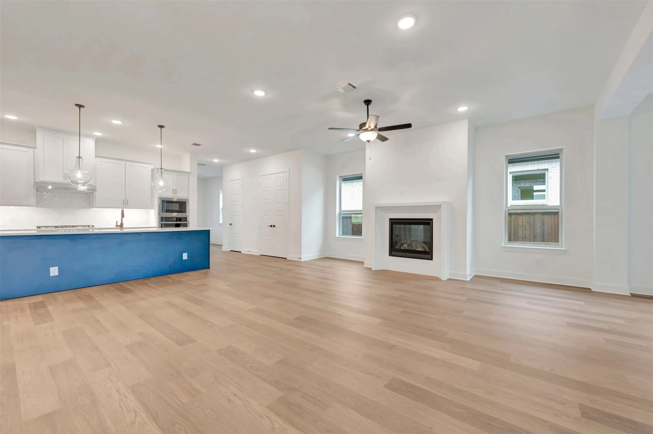 Open concept living space featuring wood-finish flooring, a contemporary fireplace, and recessed lighting