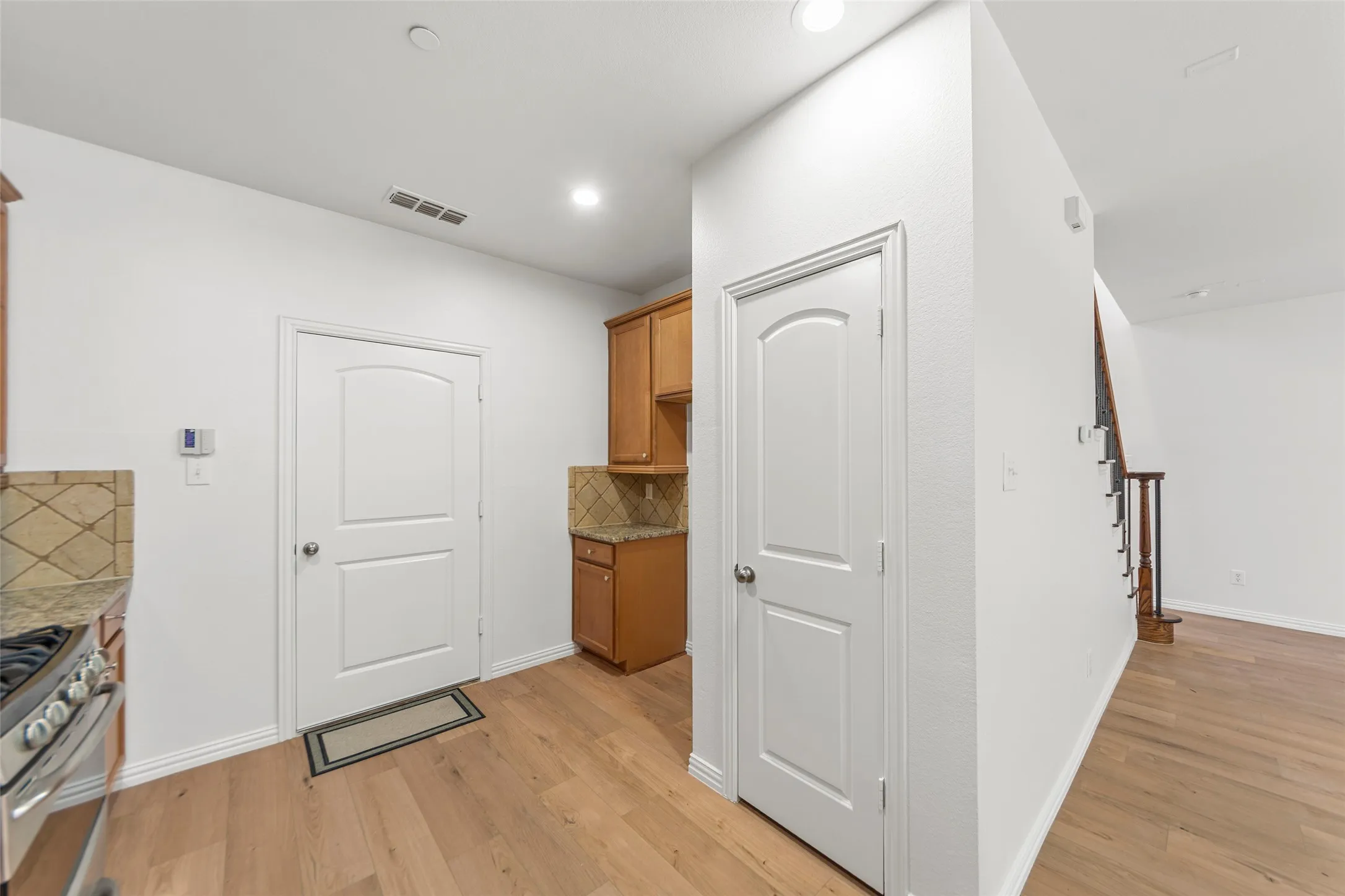 Kitchen area featuring light wood-finish flooring, white paneled doors, and recessed lighting
