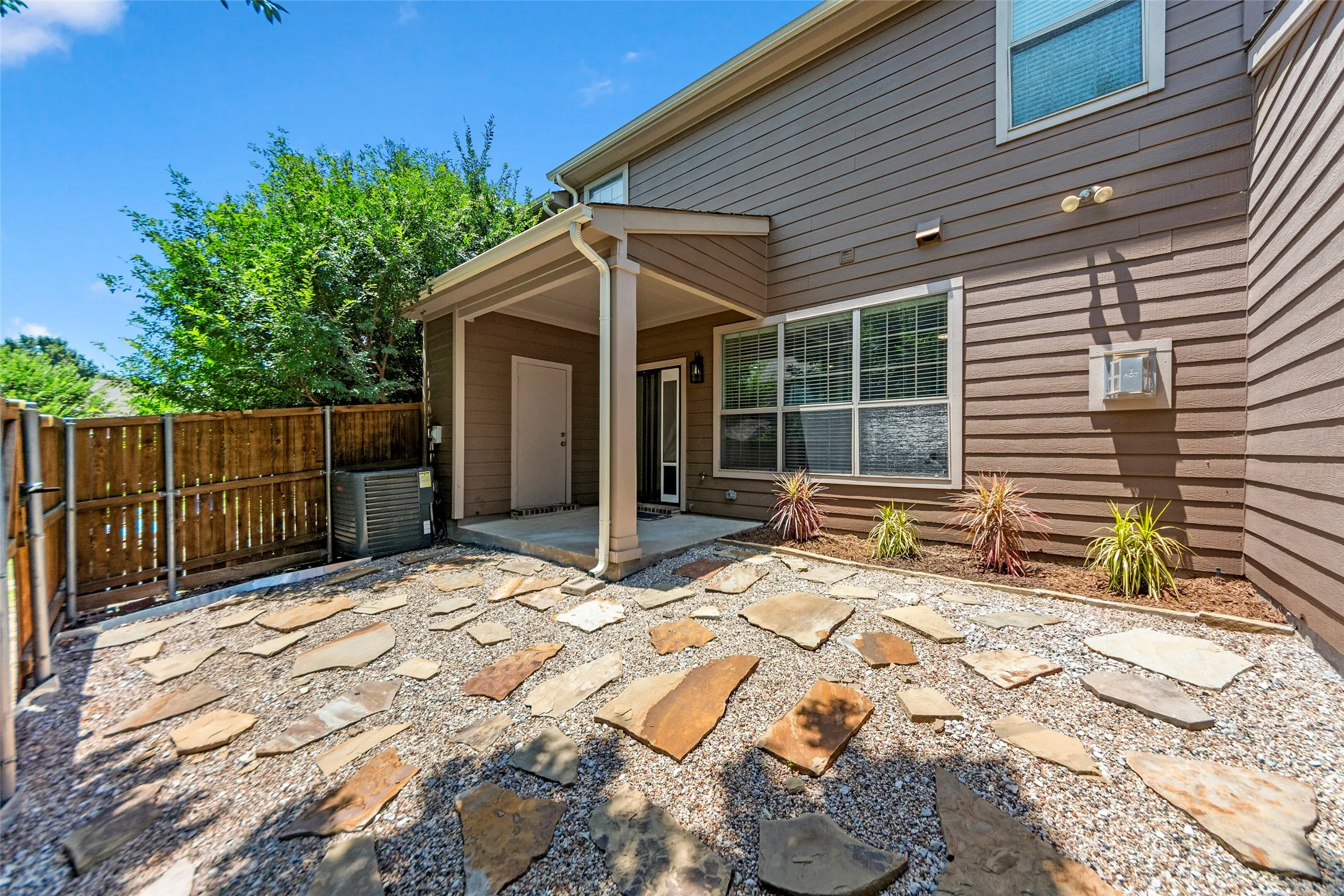 Private outdoor space featuring stone pavers and gravel landscaping, with a covered patio area