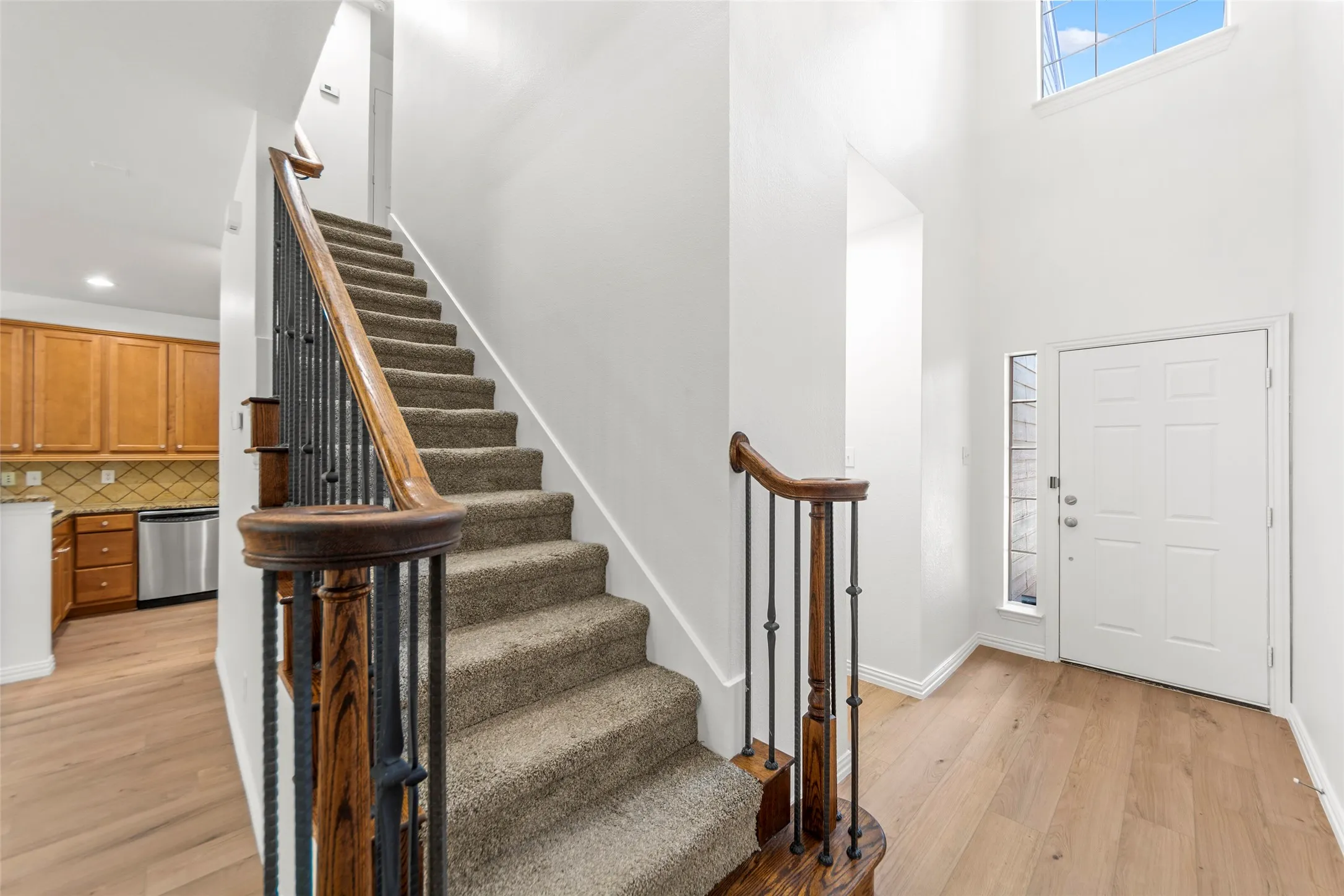 Entryway with light wood-finish flooring, a white paneled door, and a tall sidelight window