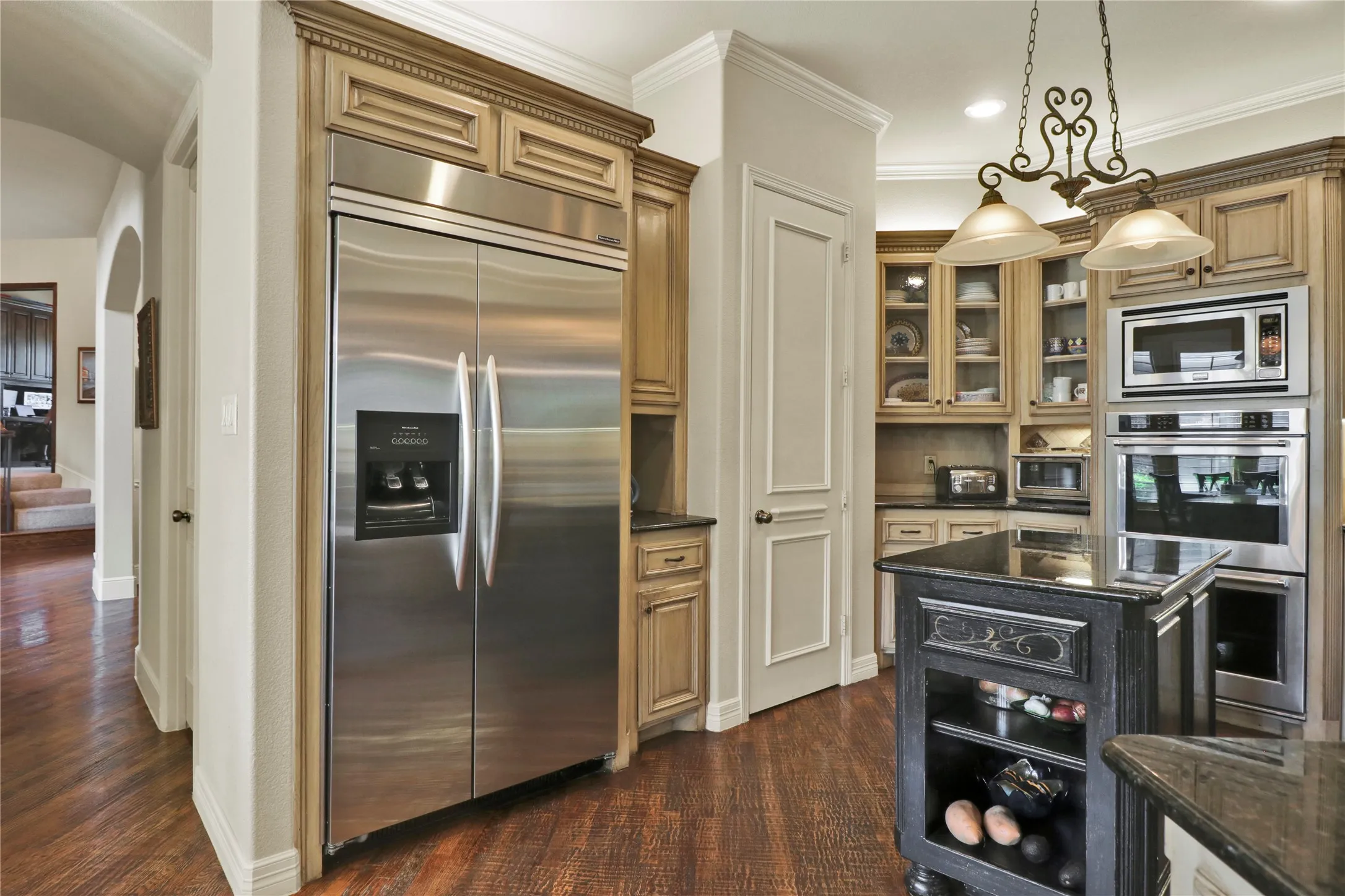 Another view of kitchen with double oven and glass panels on cabinet doors.
