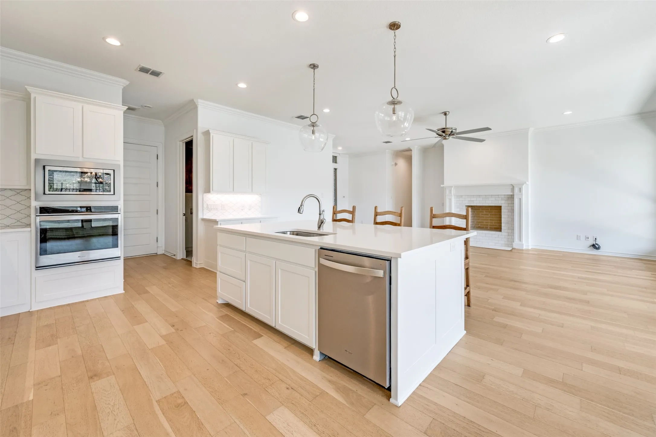 Open-concept living area featuring a kitchen island with seating, stainless steel dishwasher, and a built-in oven and microwave