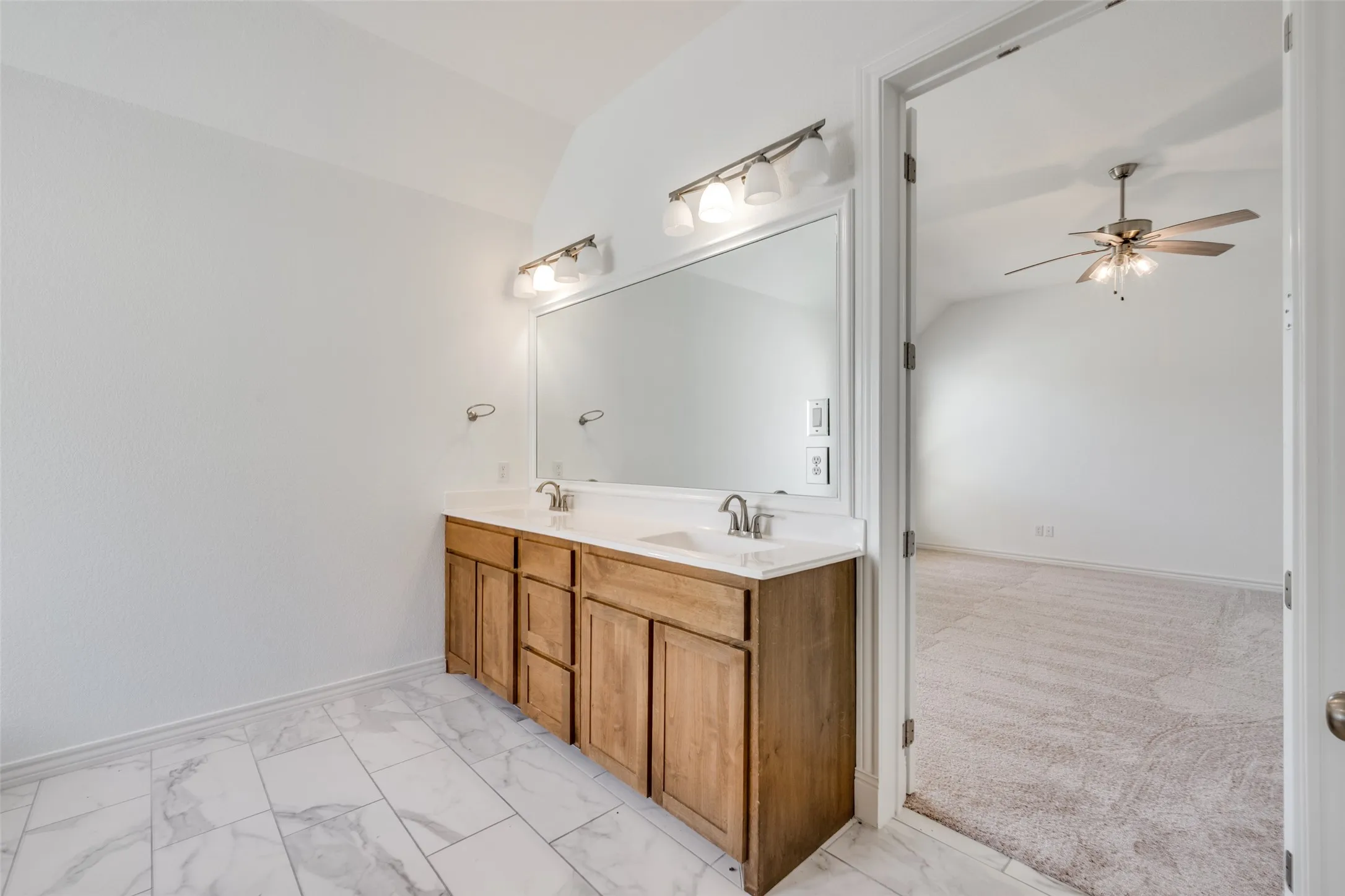 Bathroom vanity featuring dual sinks, a large framed mirror, and two brushed nickel light fixtures
