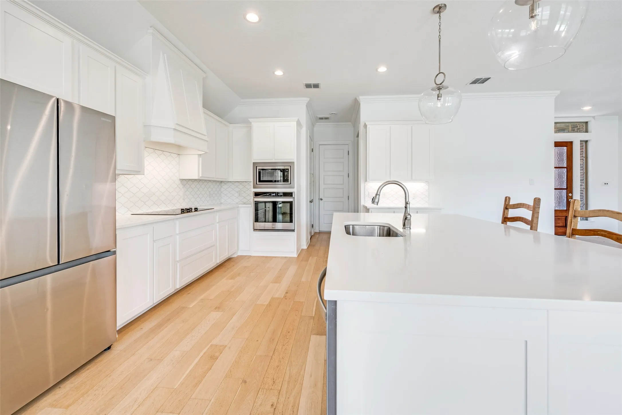 Bright kitchen featuring a large central island with an undermount sink and gooseneck faucet