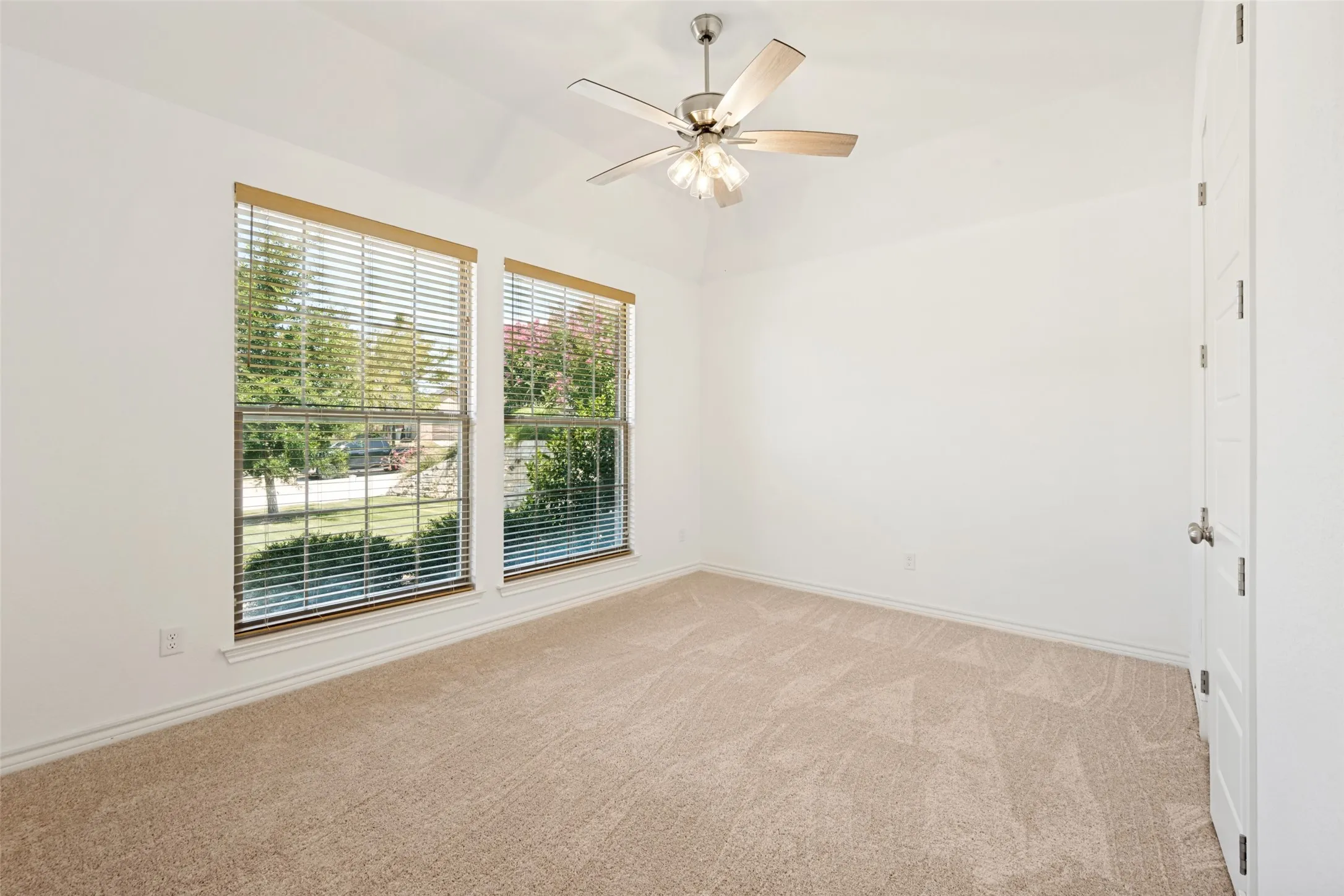Spacious room featuring vaulted ceilings, neutral-toned carpet, and two large windows with blinds