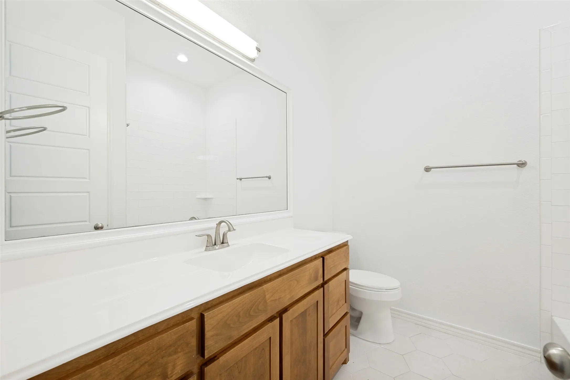 Bathroom featuring a wood-finish vanity with a white countertop and an integrated sink