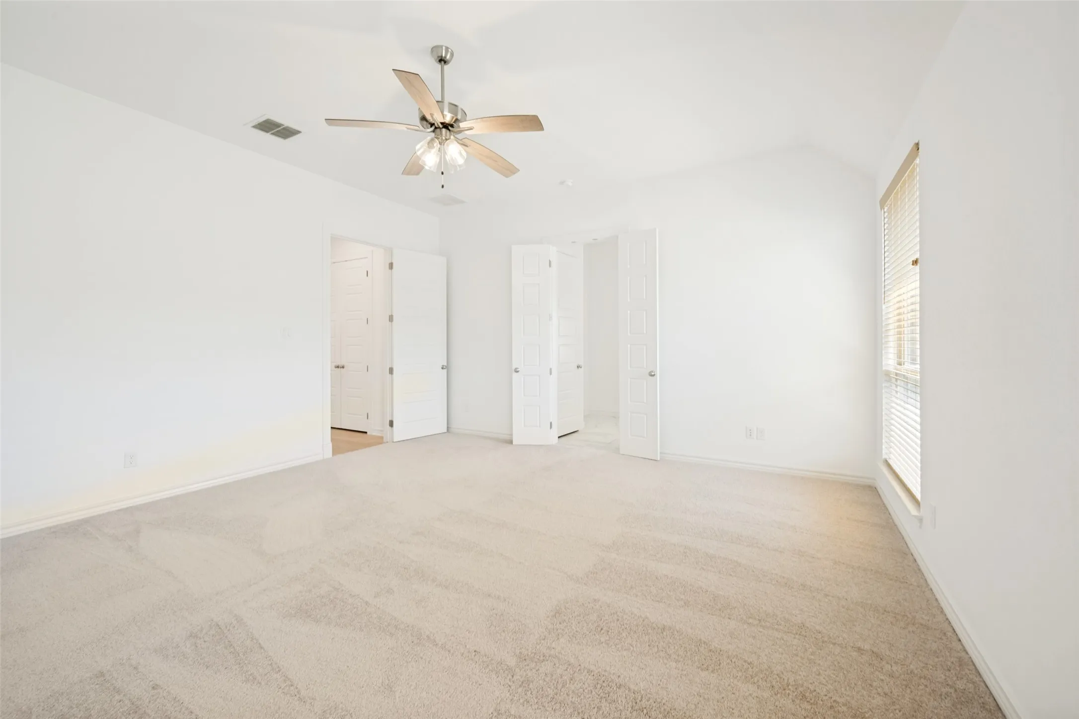 Spacious room featuring vaulted ceilings and neutral-toned carpeting