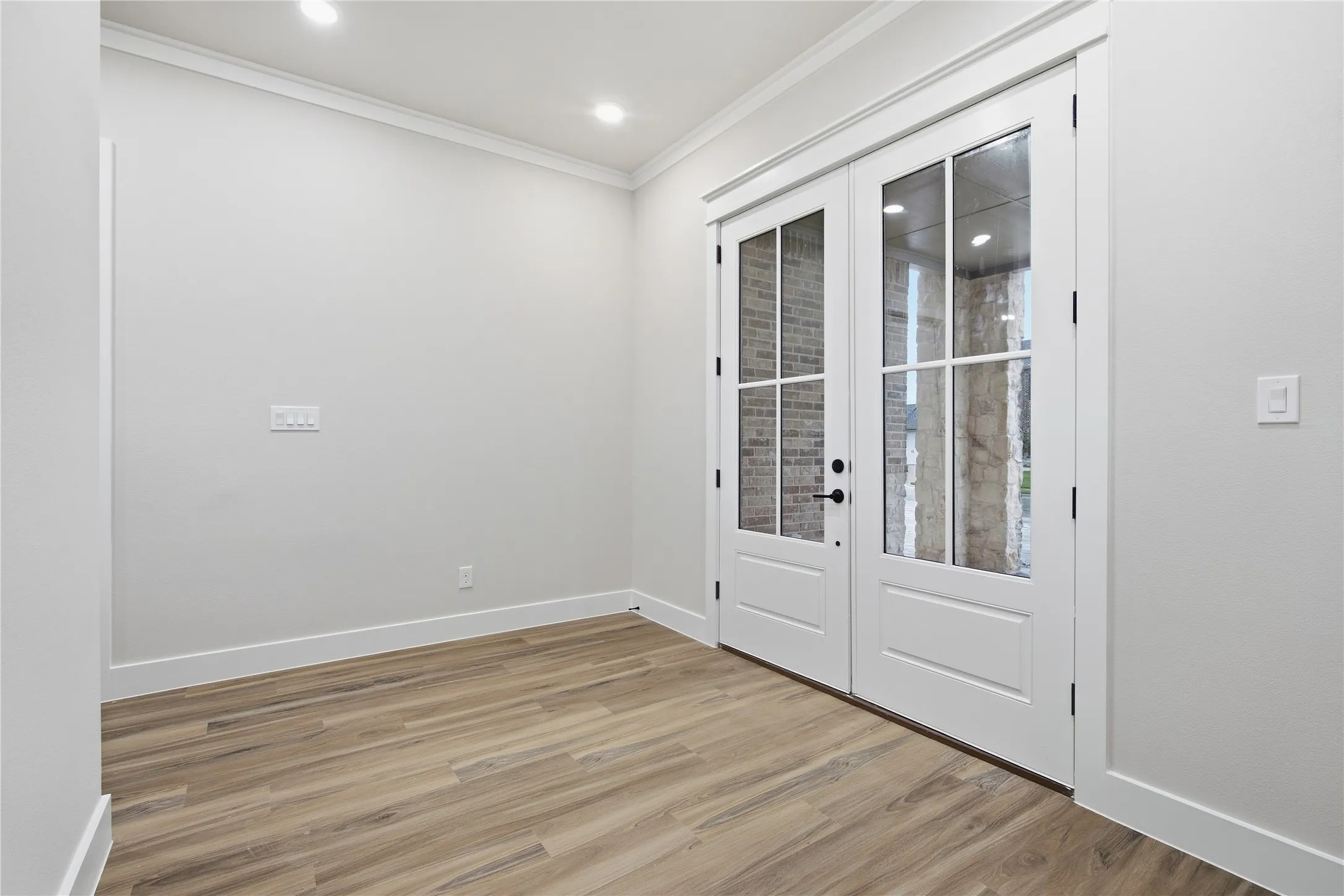 Double French doors with divided lites, wood-finish flooring, and recessed lighting