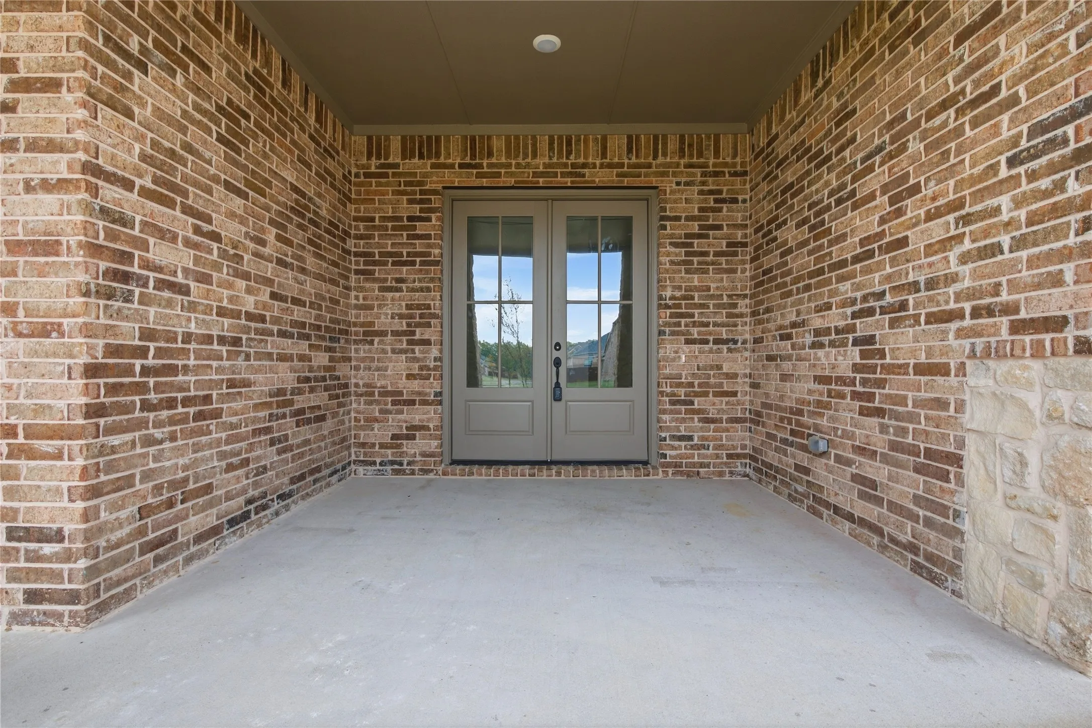 Expansive concrete patio with mixed-tone brick walls and stone veneer accents