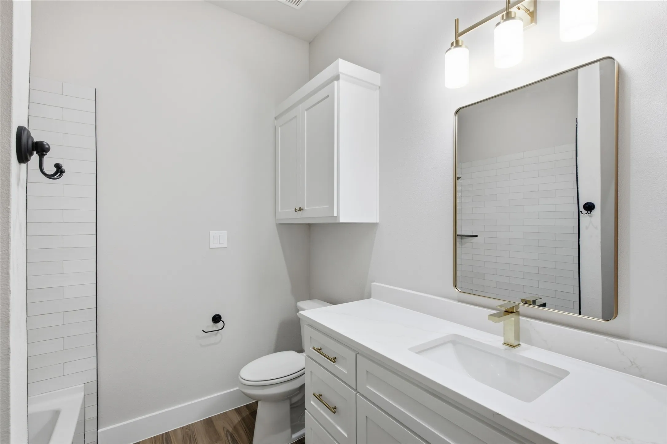 White vanity with gold-finish hardware, integrated rectangular sink, and light countertop