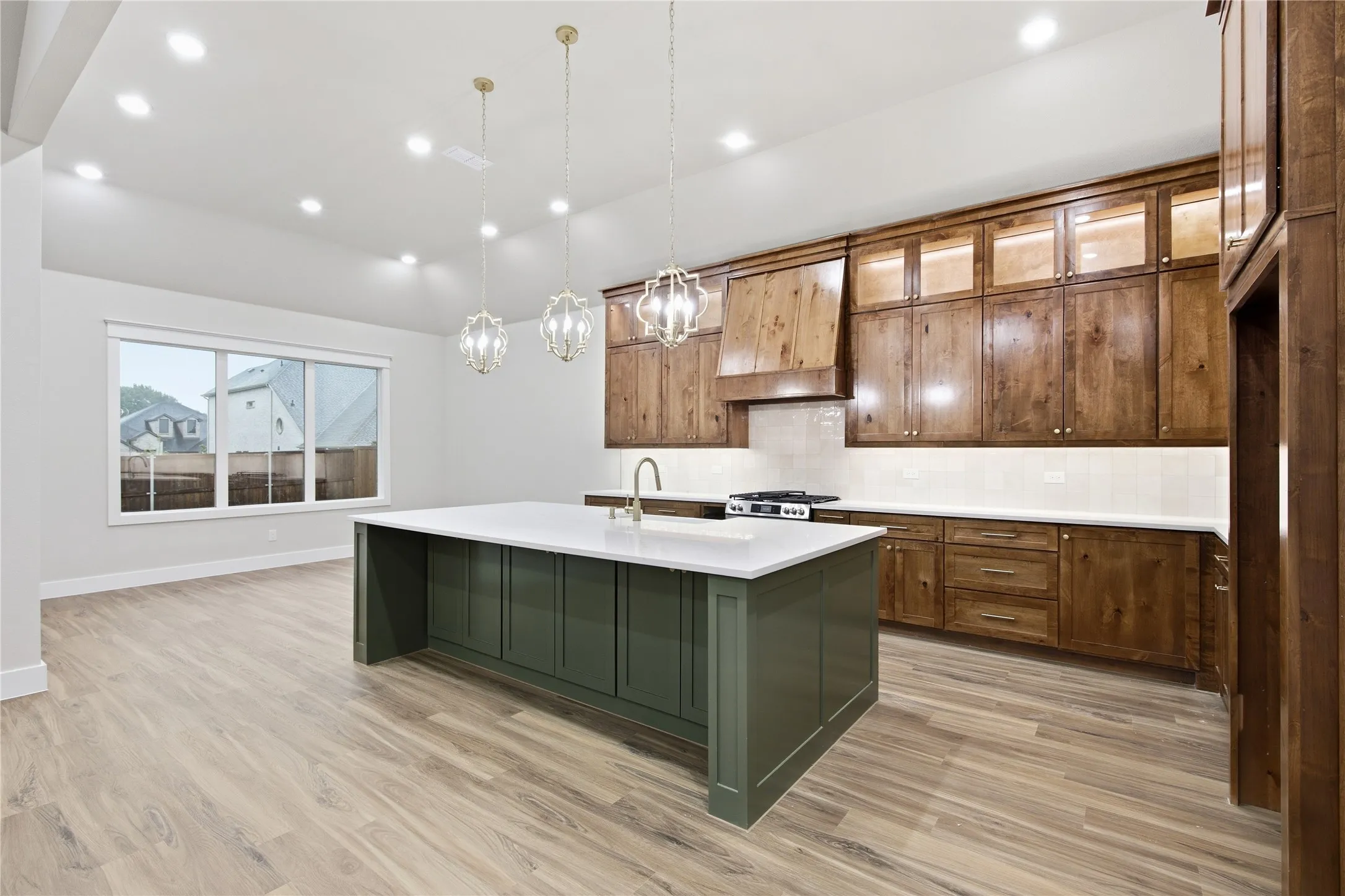 Expansive kitchen featuring a large island with a white countertop, rich wood cabinetry, and a tile backsplash