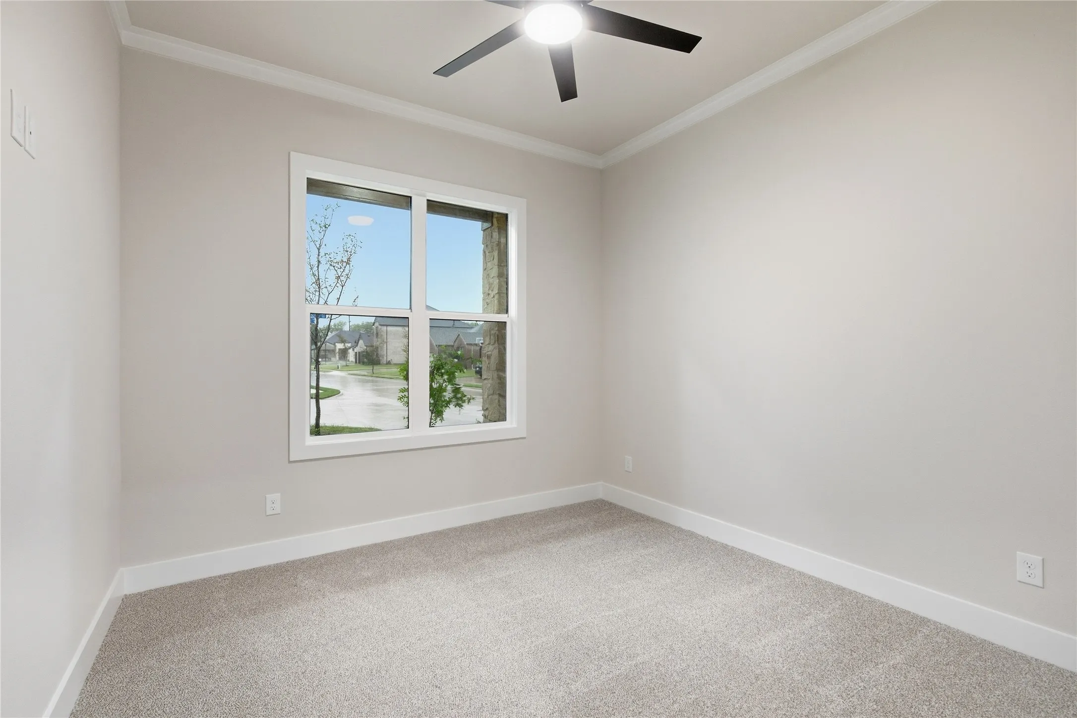 Neutral-toned walls with crown molding, light gray carpeting, and a window with white trim