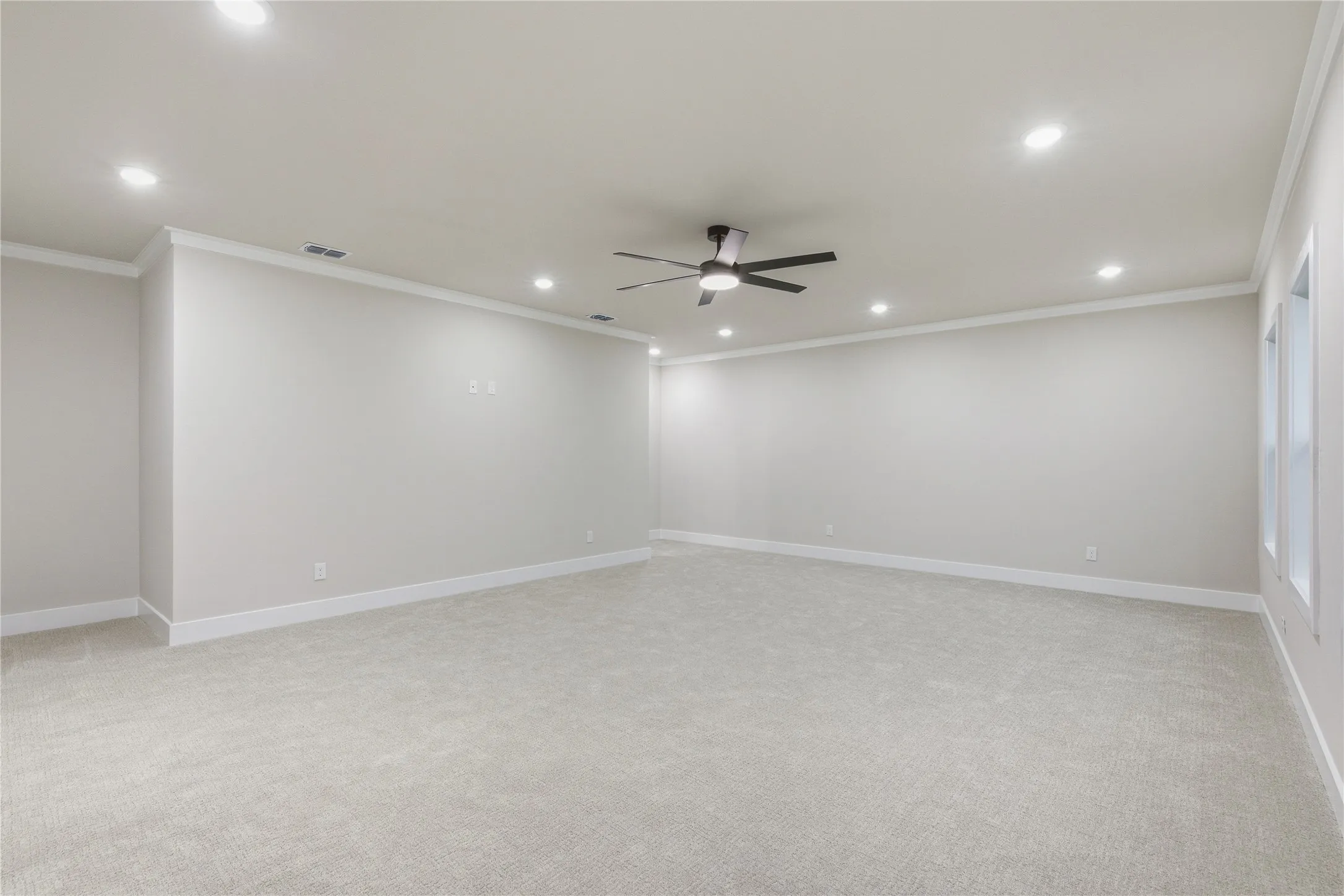 Recessed lighting, crown molding, ceiling fan, neutral paint, and light-colored carpeting