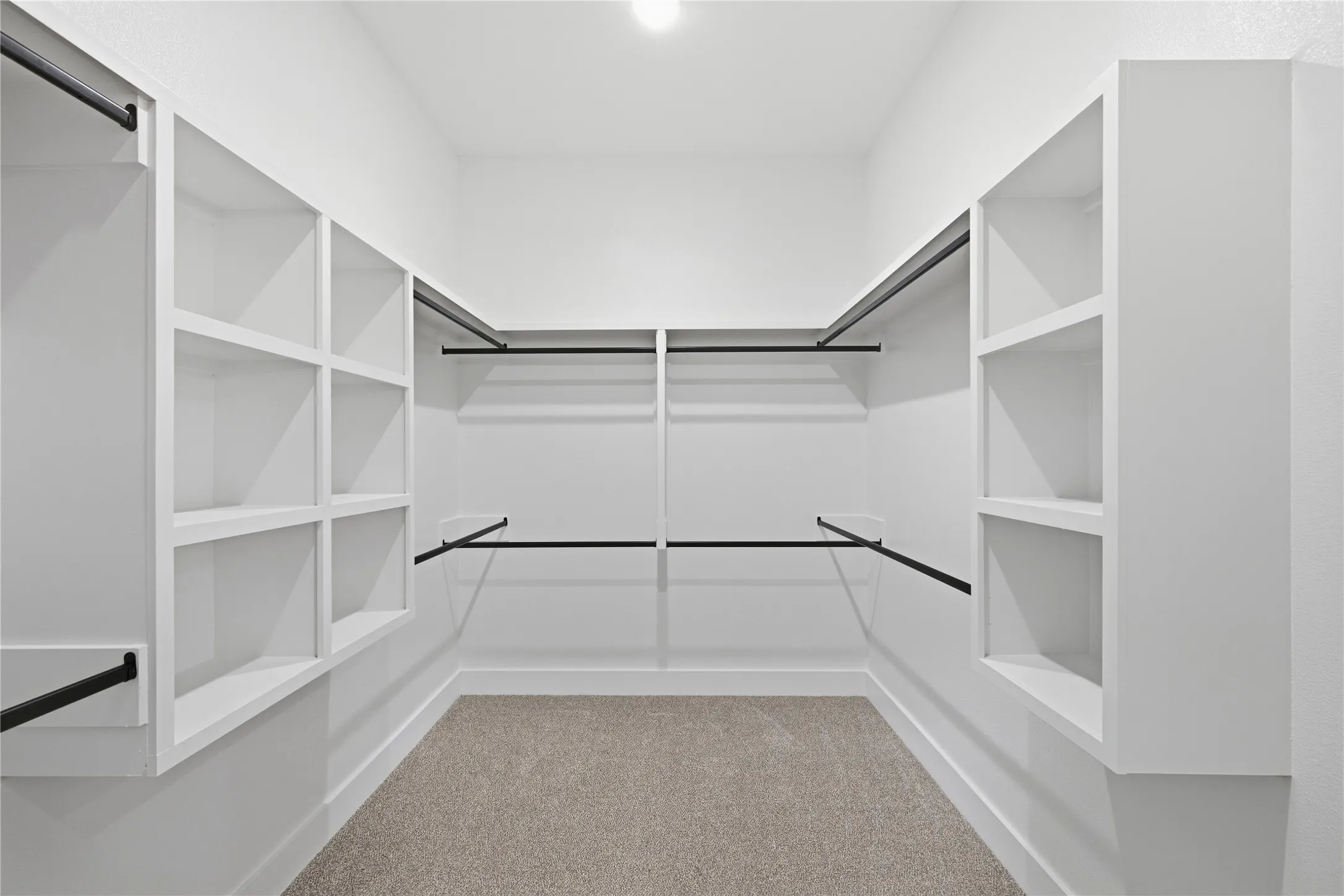 Built-in shelving units, multiple hanging rods, recessed lighting, and carpeting create a functional space